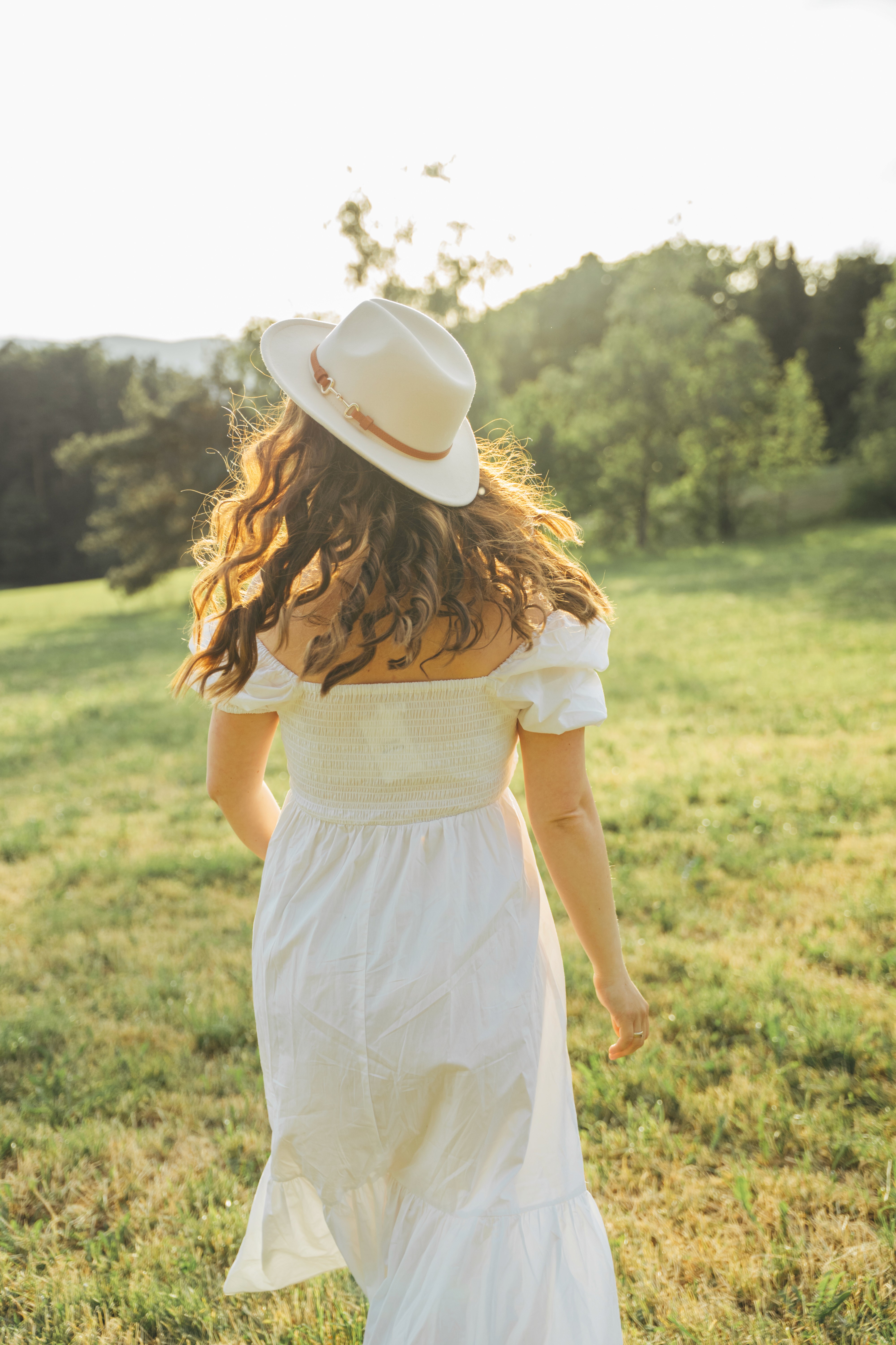 Schwangerschaftsfotografie in Bogen, Bayern – werdende Mutter von hinten im weißen Kleid im Grünen.