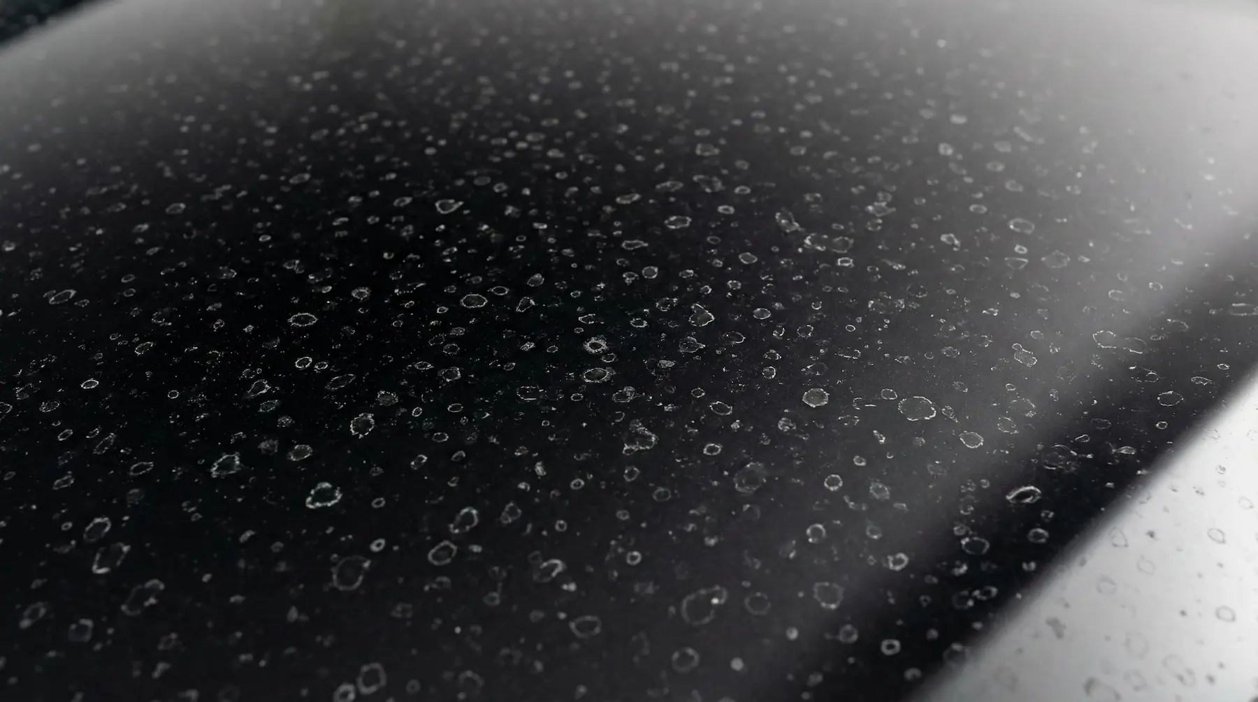 Traces de calcaire sur une carrosserie noire en gros plan