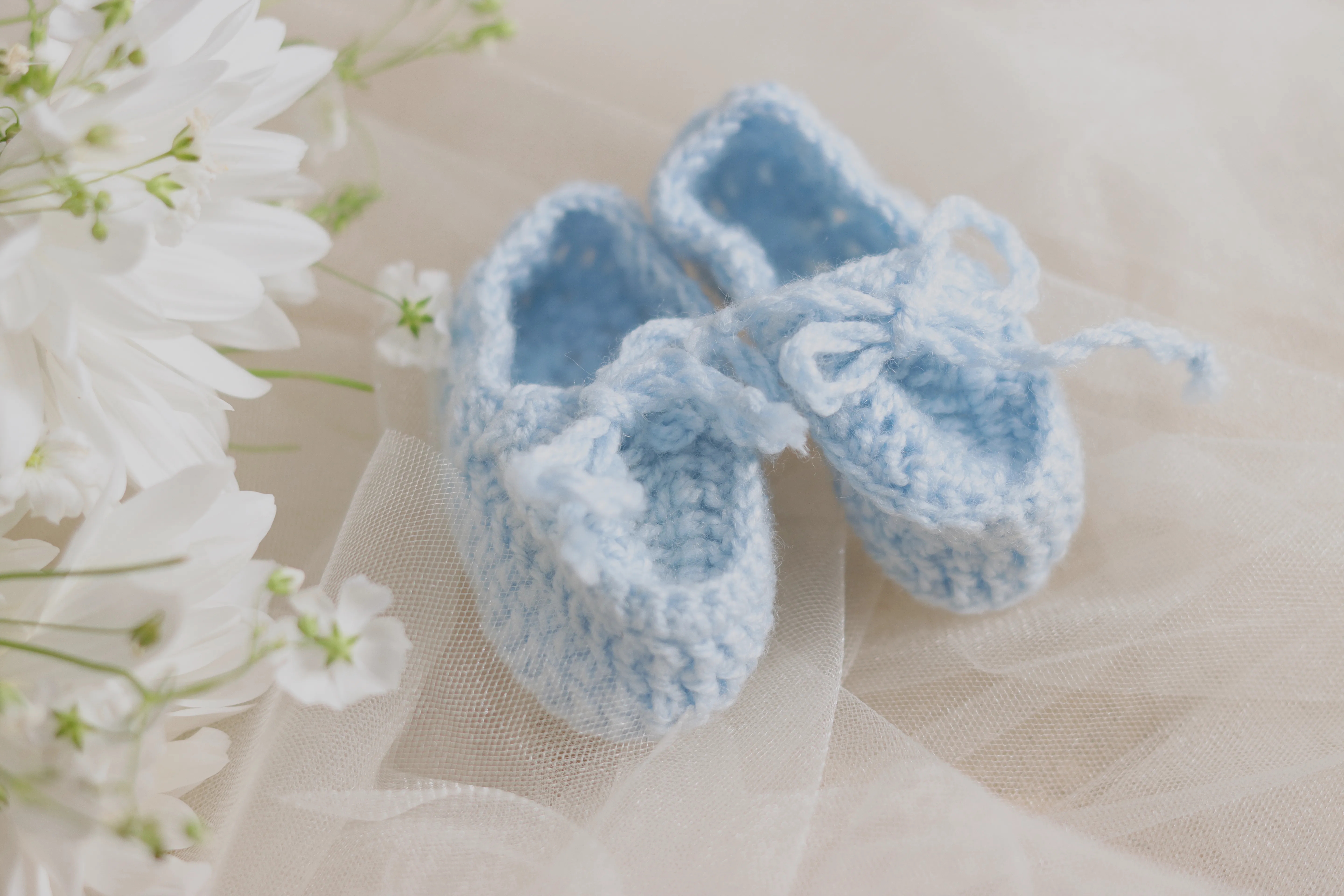 Pequeños zapatitos de bebé sobre tela blanca y tul