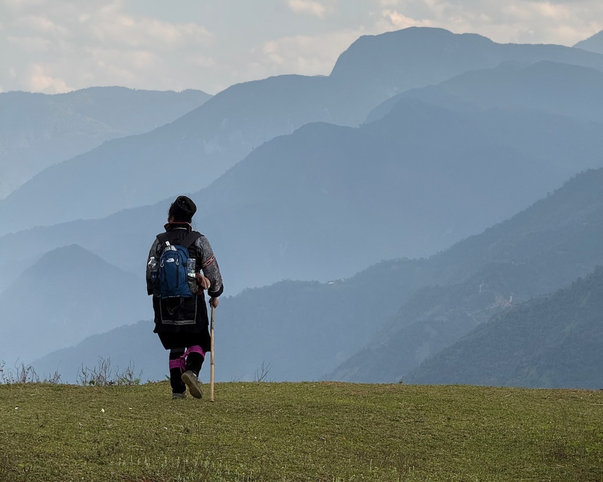 Pang standing on a mountain viewpoint overlooking the peaks around Sapa, Vietnam.
