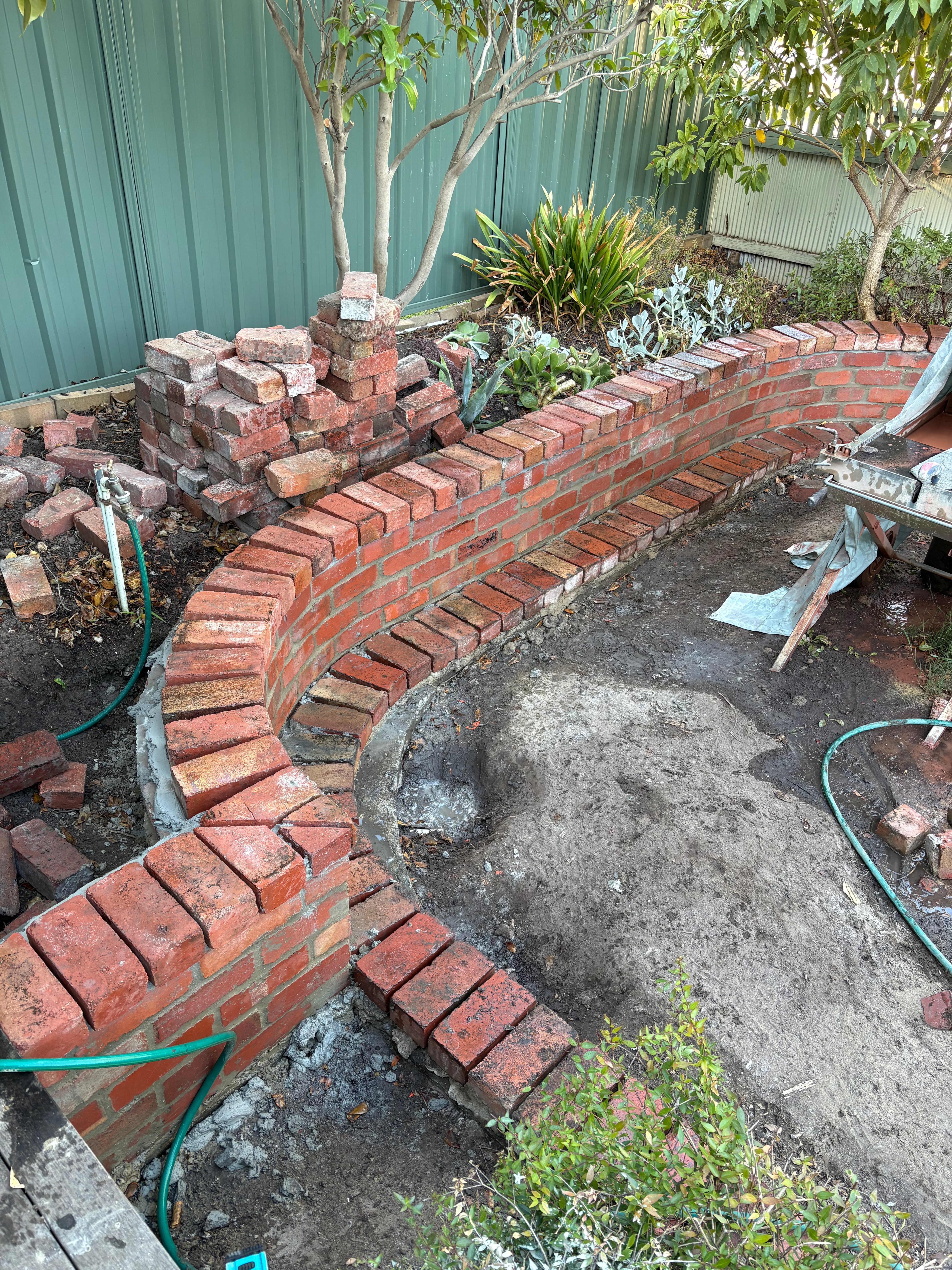 Curved brick wall under construction in a garden.