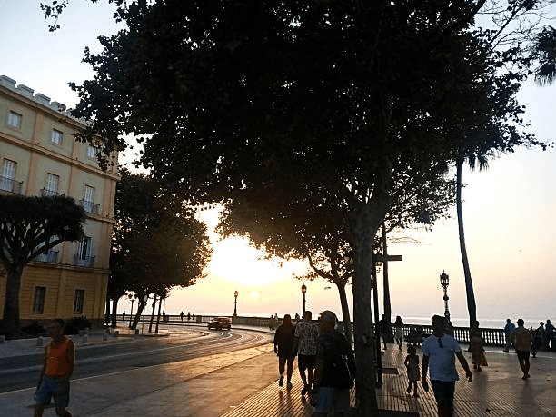 Locals walking along Cádiz seaside promenade during sunset
