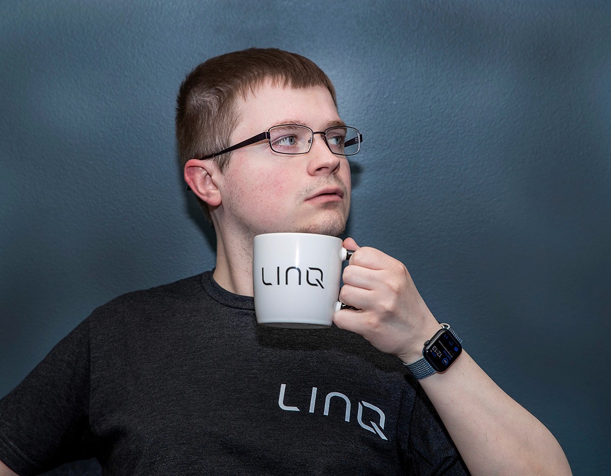 man wearing linq shirt holding a linq mug