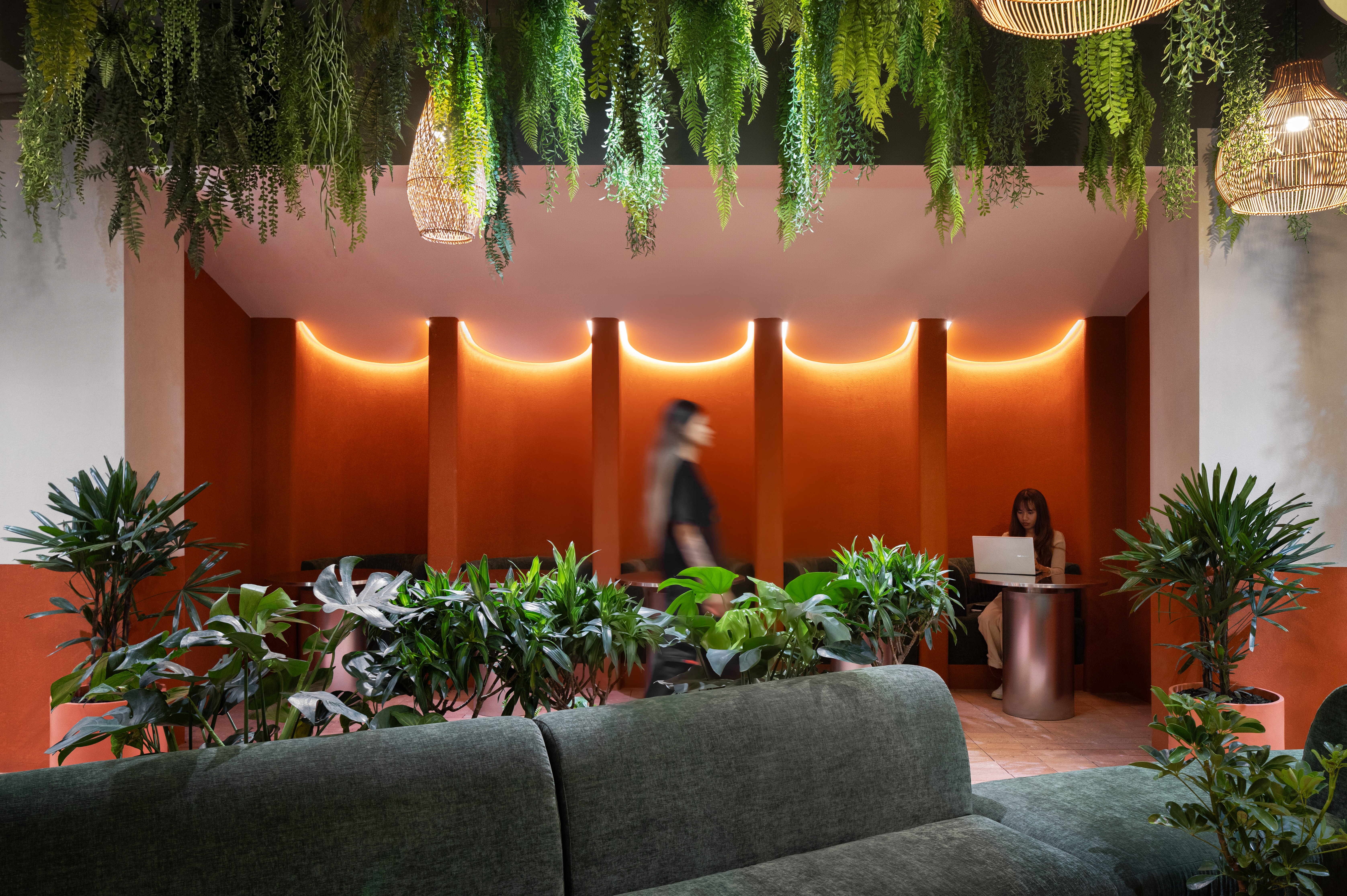 Upholstered booth niche with terracotta acoustic wall and integrated lighting, semi-enclosed seating providing speech privacy, durability, and straightforward maintainability