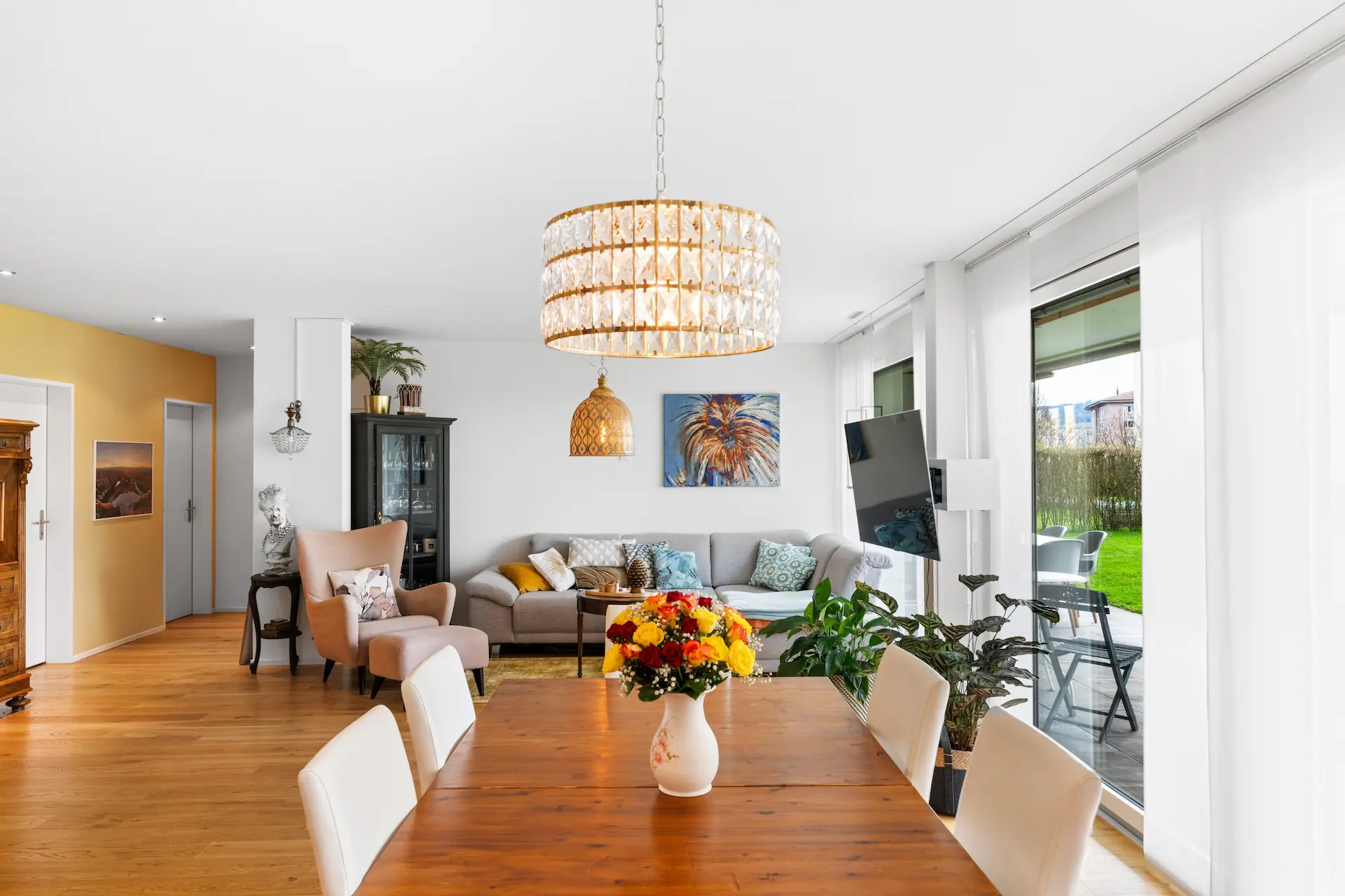 Eleganter Essbereich mit Kronleuchter und offenem Wohnzimmer im Hintergrund