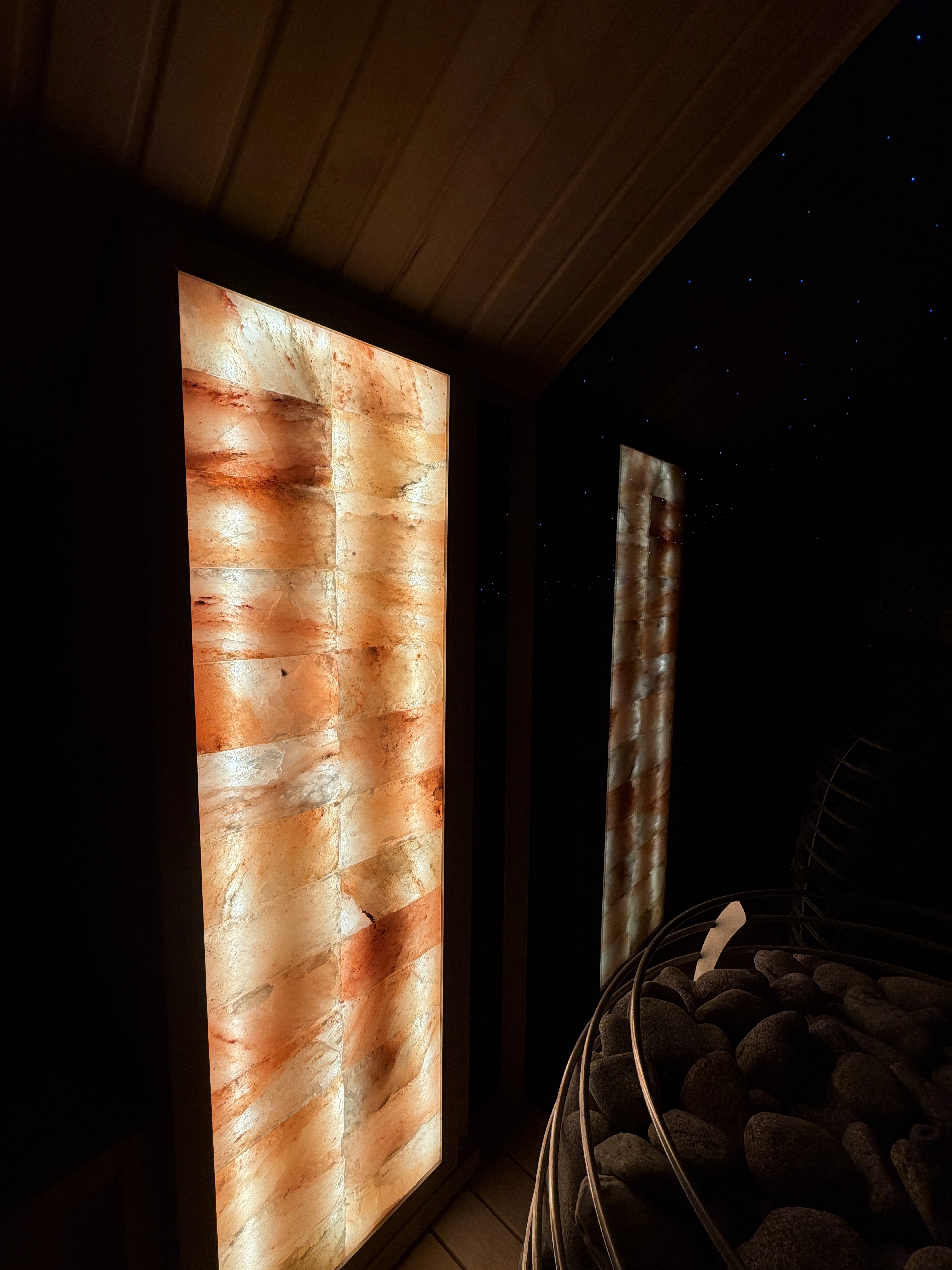Modern wooden sauna with ambient lighting and stone heater.