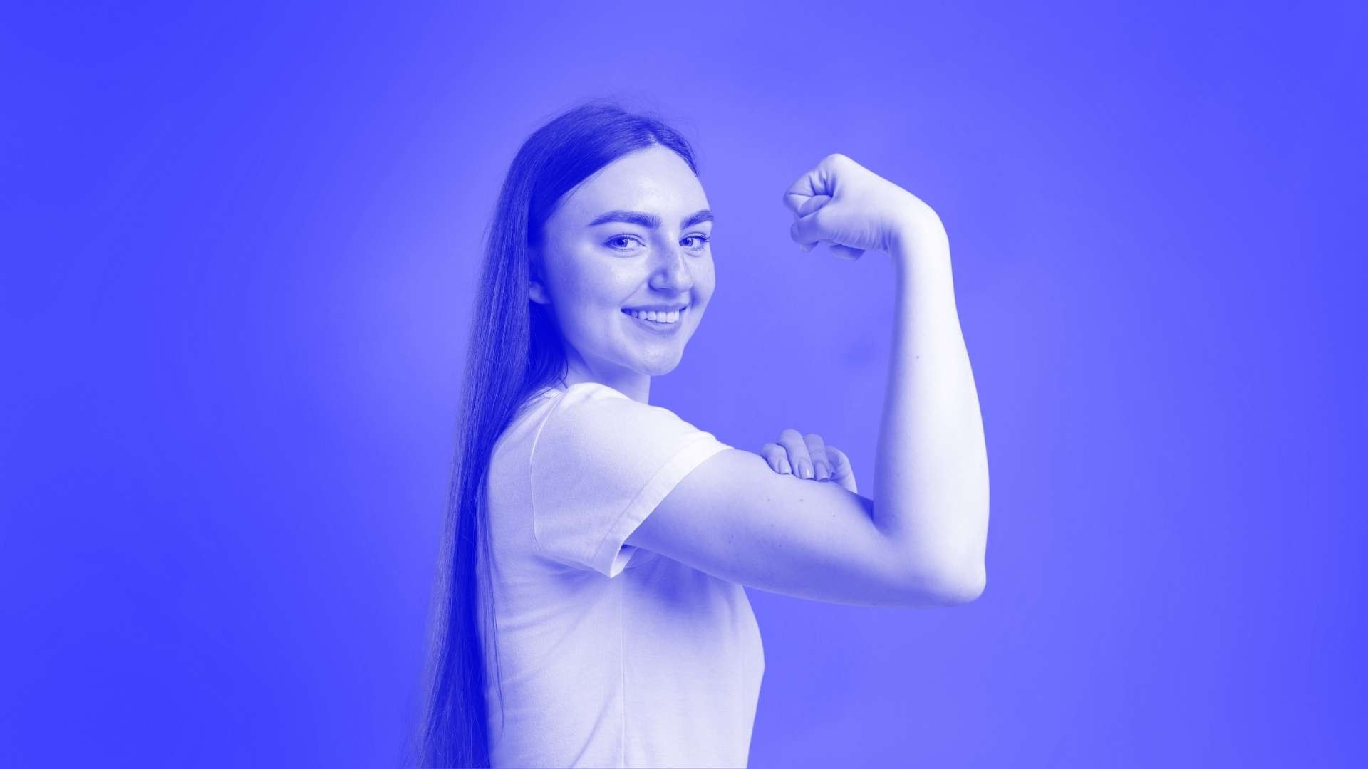 A woman smiling and lifting her arm to show that her right tricep muscle is strong