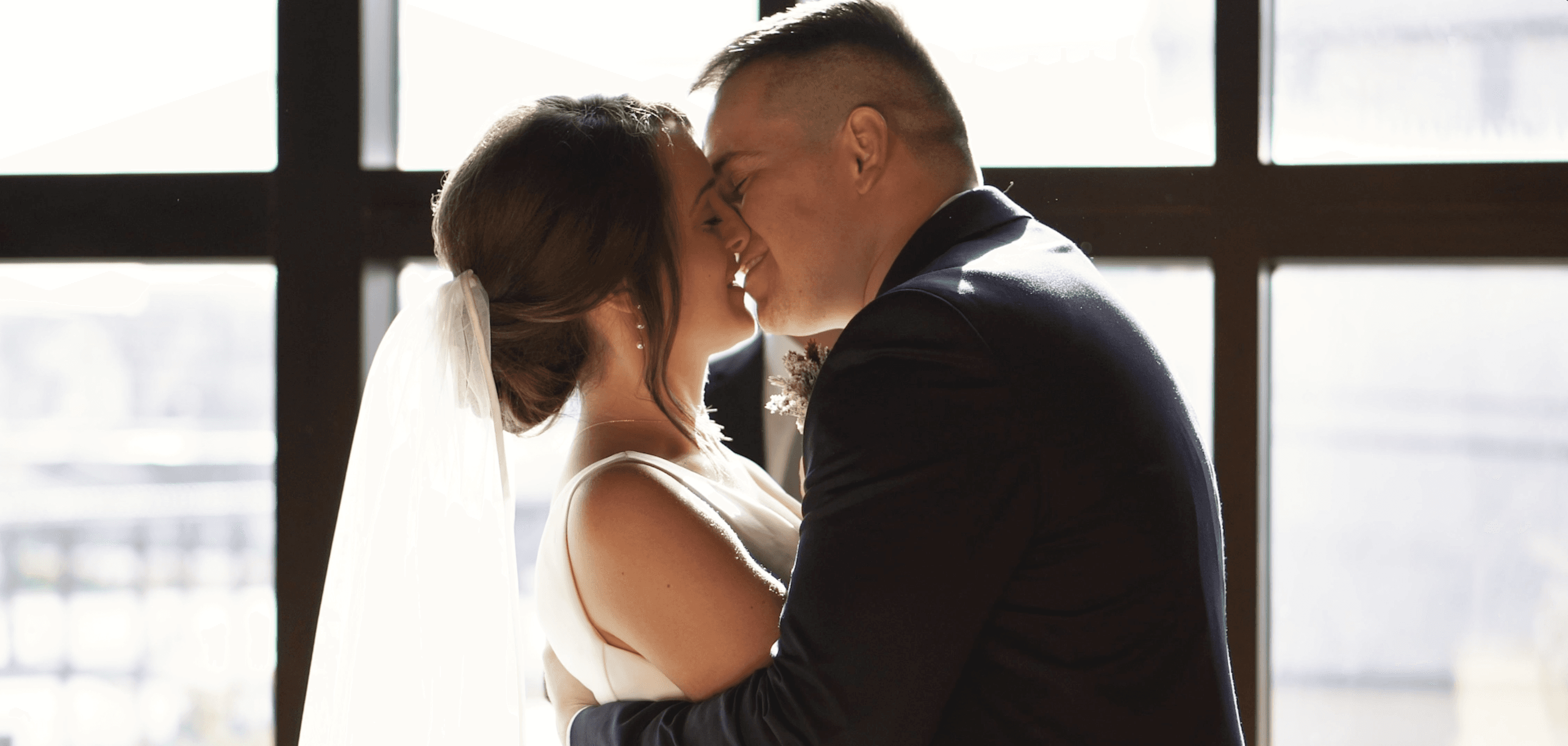 photo of a couple kissing on their wedding day with sunlight coming through the window behind them