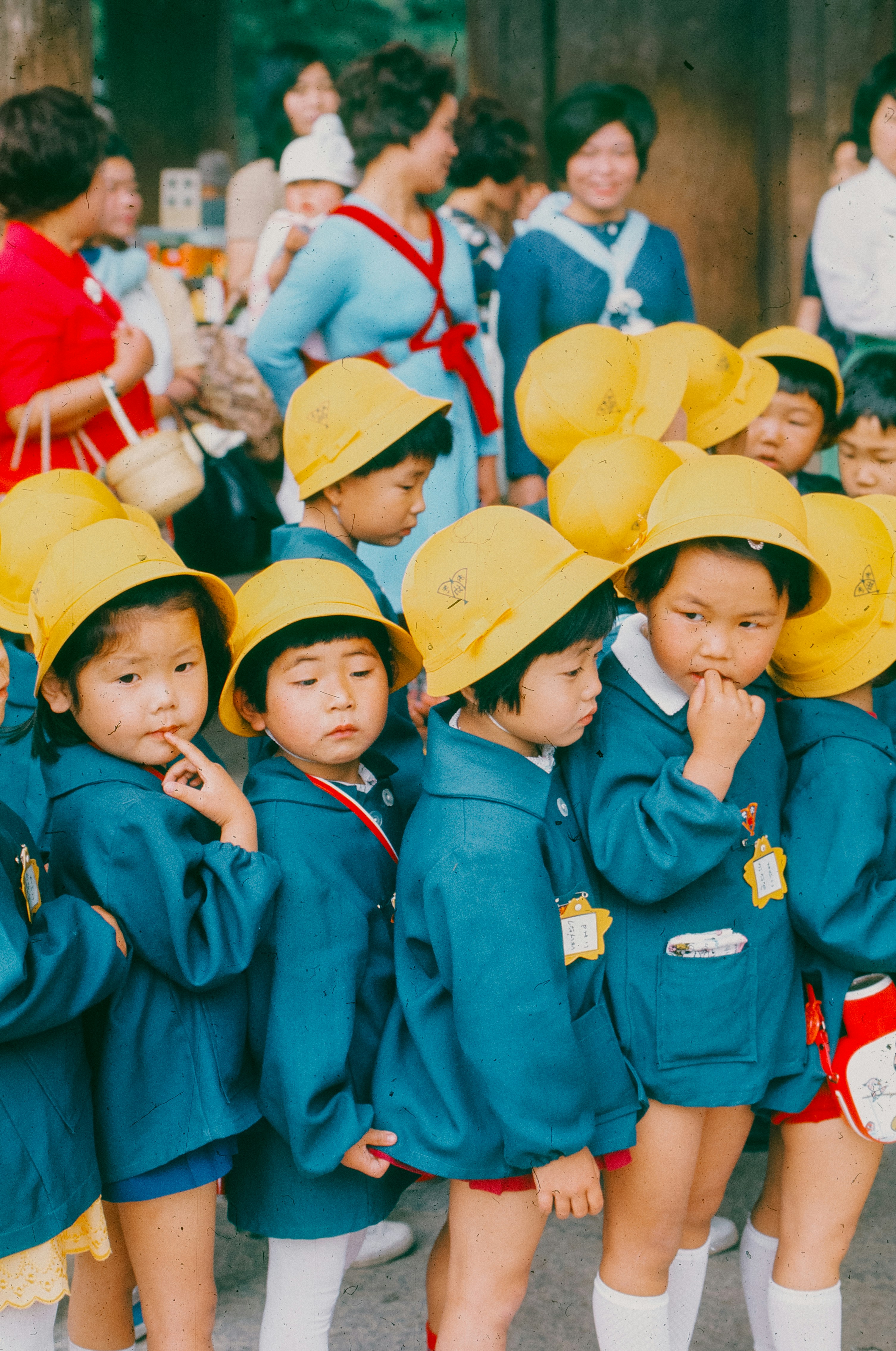 Young children in blue coats and yellow hats