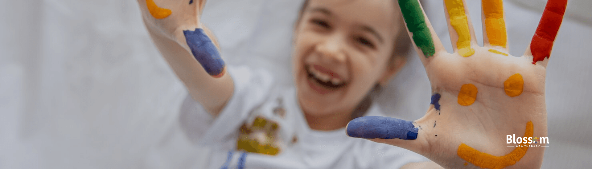 An autistic child lying on the bed raising her painted hands