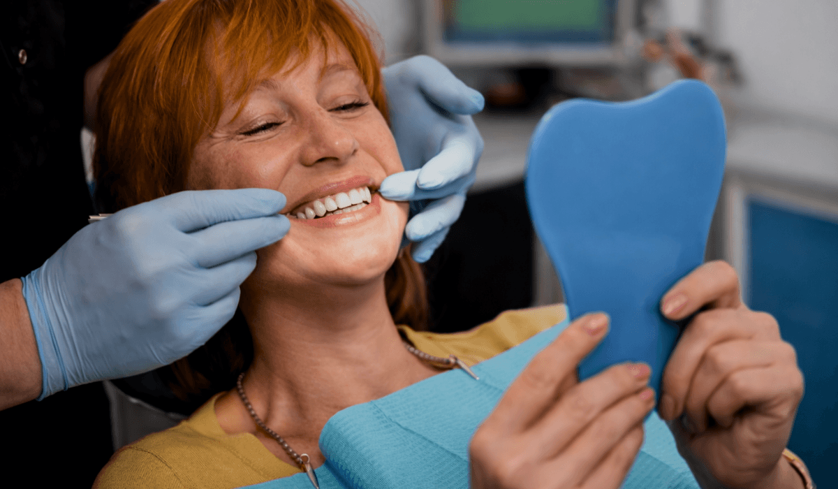 paciente satisfeito vendo seu novo sorriso no espelho