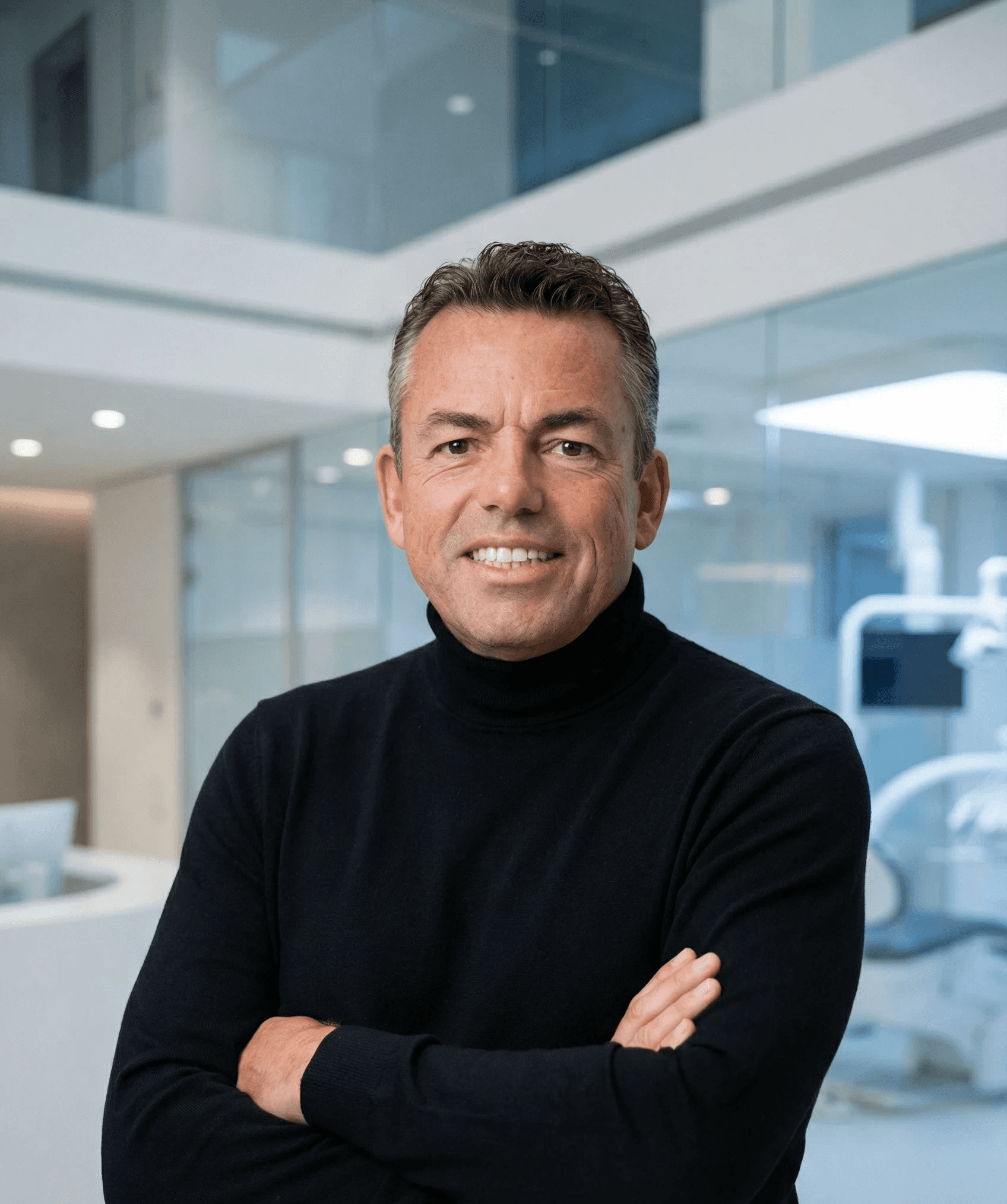 Woman with a short haircut smiling confidently, wearing a blazer and standing in warm natural light with modern architecture behind her.