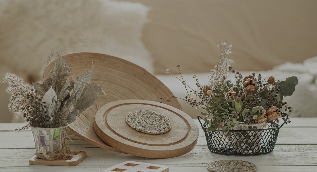 A smiling woman with curly hair is posing in a warmly lit indoor setting. She wears a dark-colored shirt.