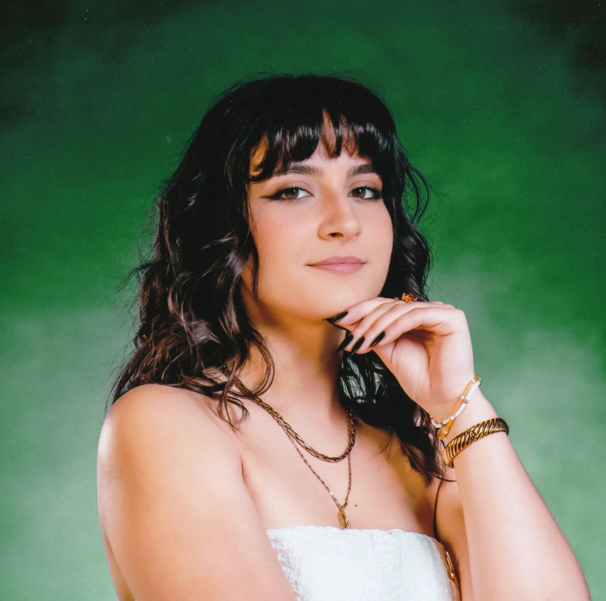 Portrait studio de la directrice artistique et graphiste fondatrice de Tartelette Concept à Toulouse, Anaïs Humbert, sur fond vert texturé.