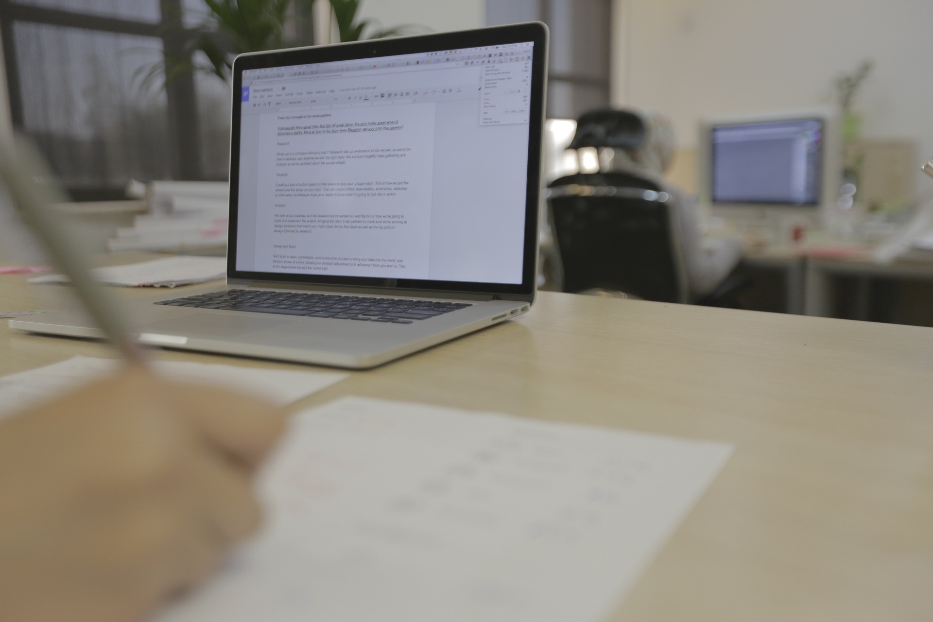 Open laptop and handwritten notes on a shared desk in Plexable's Amman office