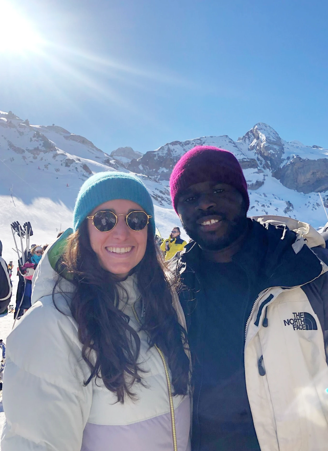 A woman with long blonde hair, in a brown top and jeans, walks through a sunlit forest, holding someone's hand. The scene is warm and inviting.