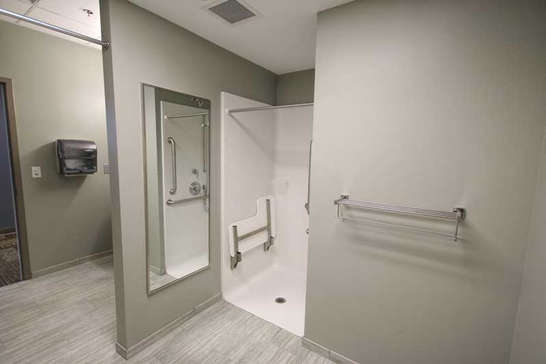 Modern bathroom with a glass shower, a towel rack, and minimalistic decor in neutral tones.
