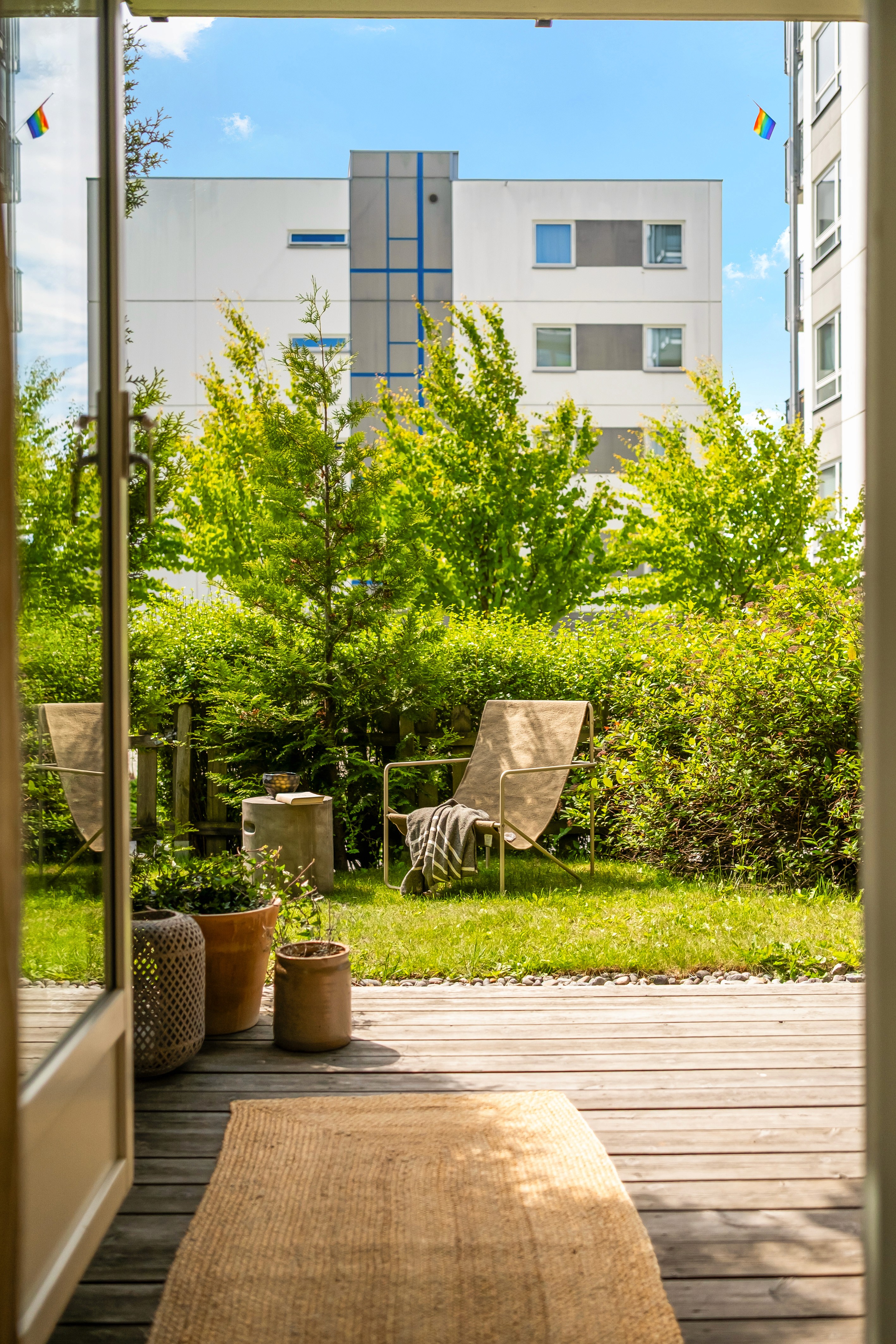 Hage med grønne busker sett fra åpen verandadør