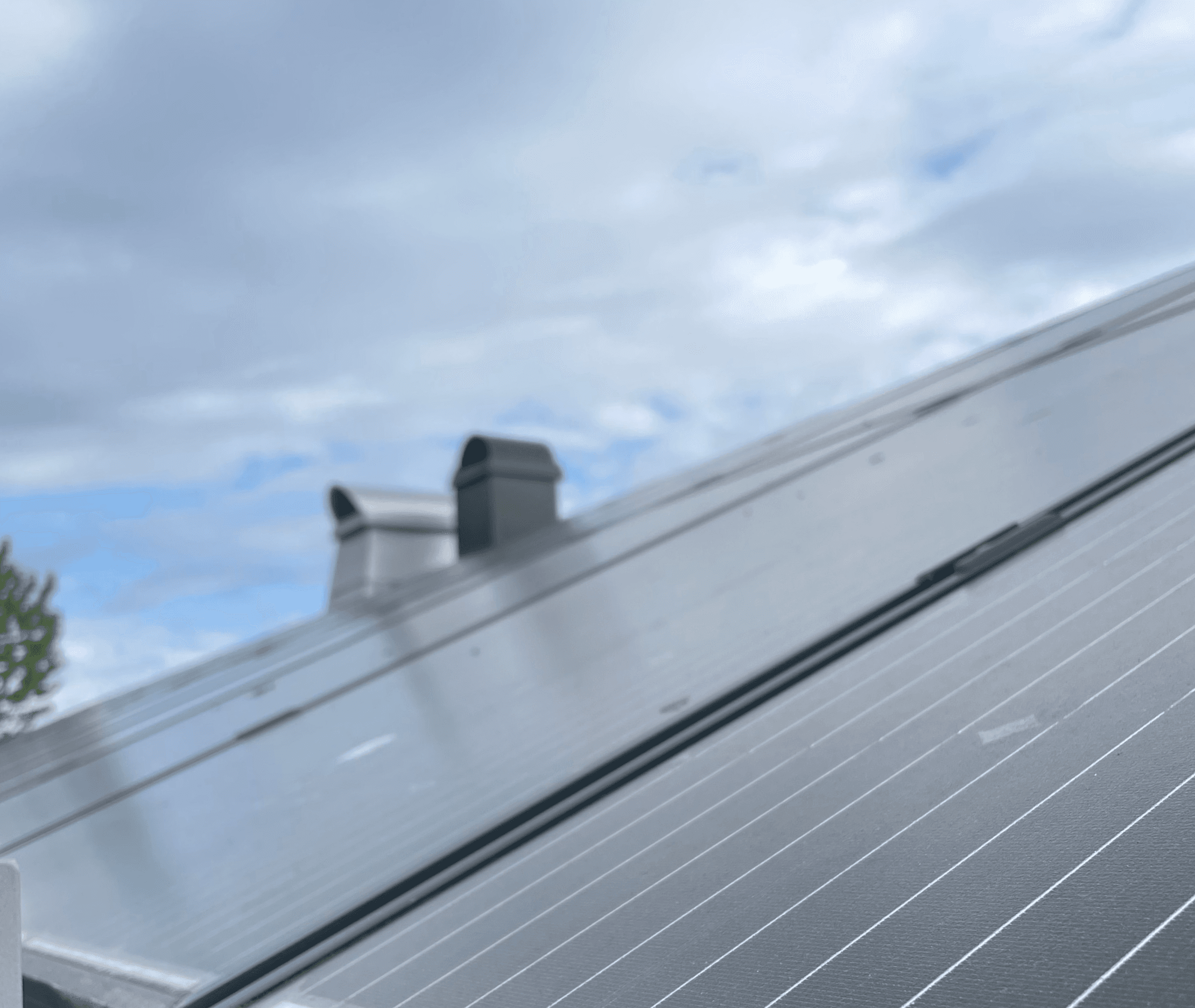 Bild på ett hustak med smutsiga solceller och två skorstenar