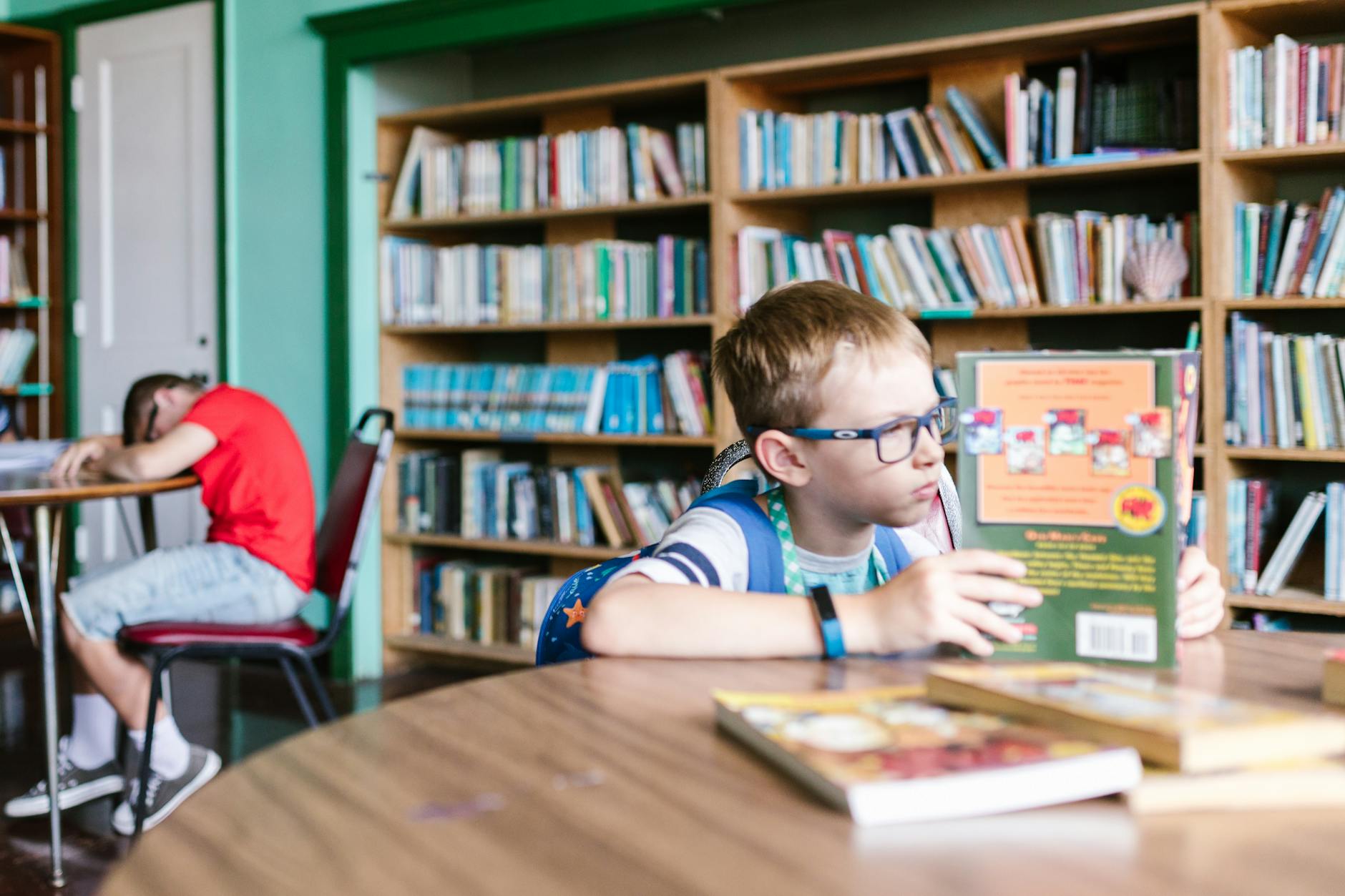 A librarian helps a student browse library shelves to find good books for 12 year olds at various reading levels.