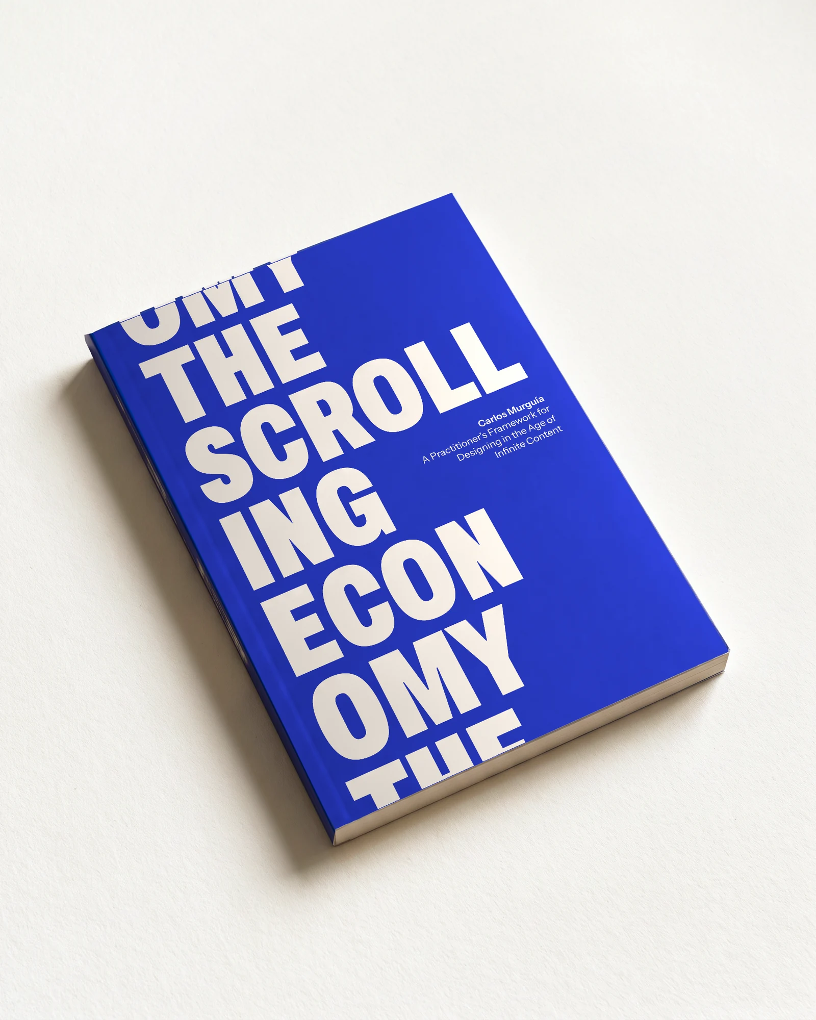 The Scrolling Economy by Carlos Murguía, a cobalt paperback lying on paper