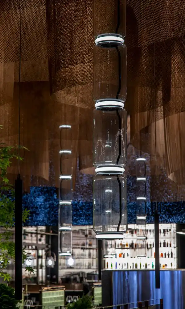 Plafond de voiles de mailles de cuivre traversé de colonnes de verre lumineuses