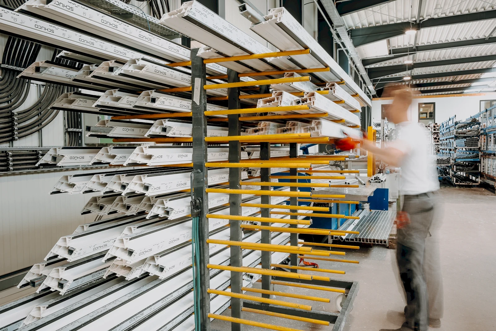 Mann an Fensterrahmenregal. Industrielle Lagerung von weißen Fensterprofilen.  Fertigungsbereich