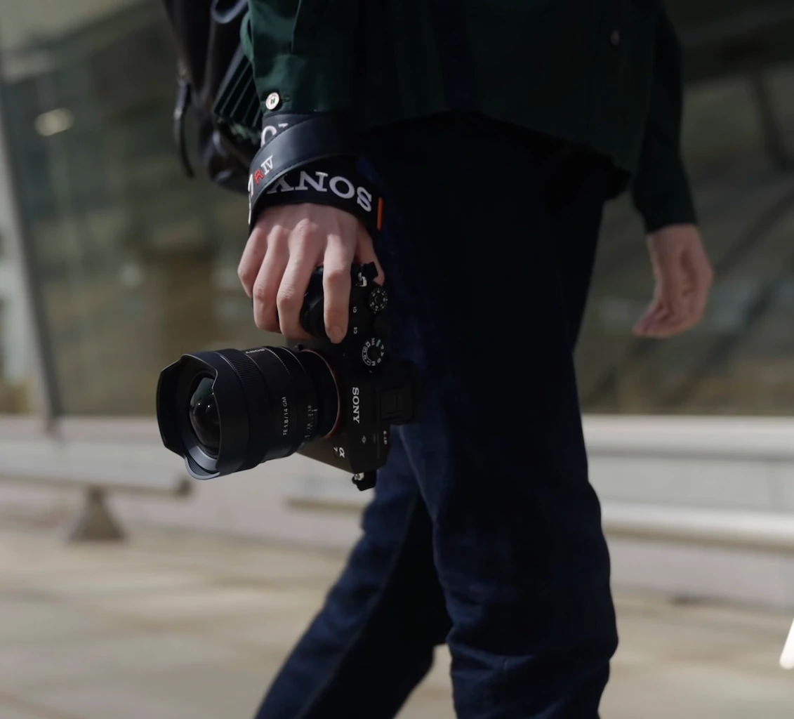 Man walking holding camera in right hand