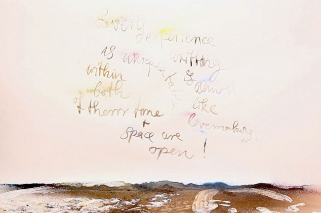 The image shows a watercolor painting on a light beige or cream-colored background. The top portion of the painting features handwritten text in black ink that reads “Every experience is writing within both space and time.” Below the text, the words “space are open!” are written in black ink. The bottom portion of the painting depicts a landscape that appears to represent a shoreline or beach, with brown and beige tones suggesting sand or earth. White and light-colored markings and splashes are visible in the bottom part of the painting, possibly representing water or waves. The painting does not contain any visible frame or border.