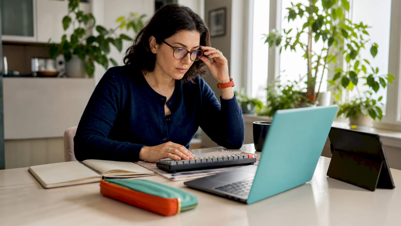 Hands typing on laptop with glossary and headset