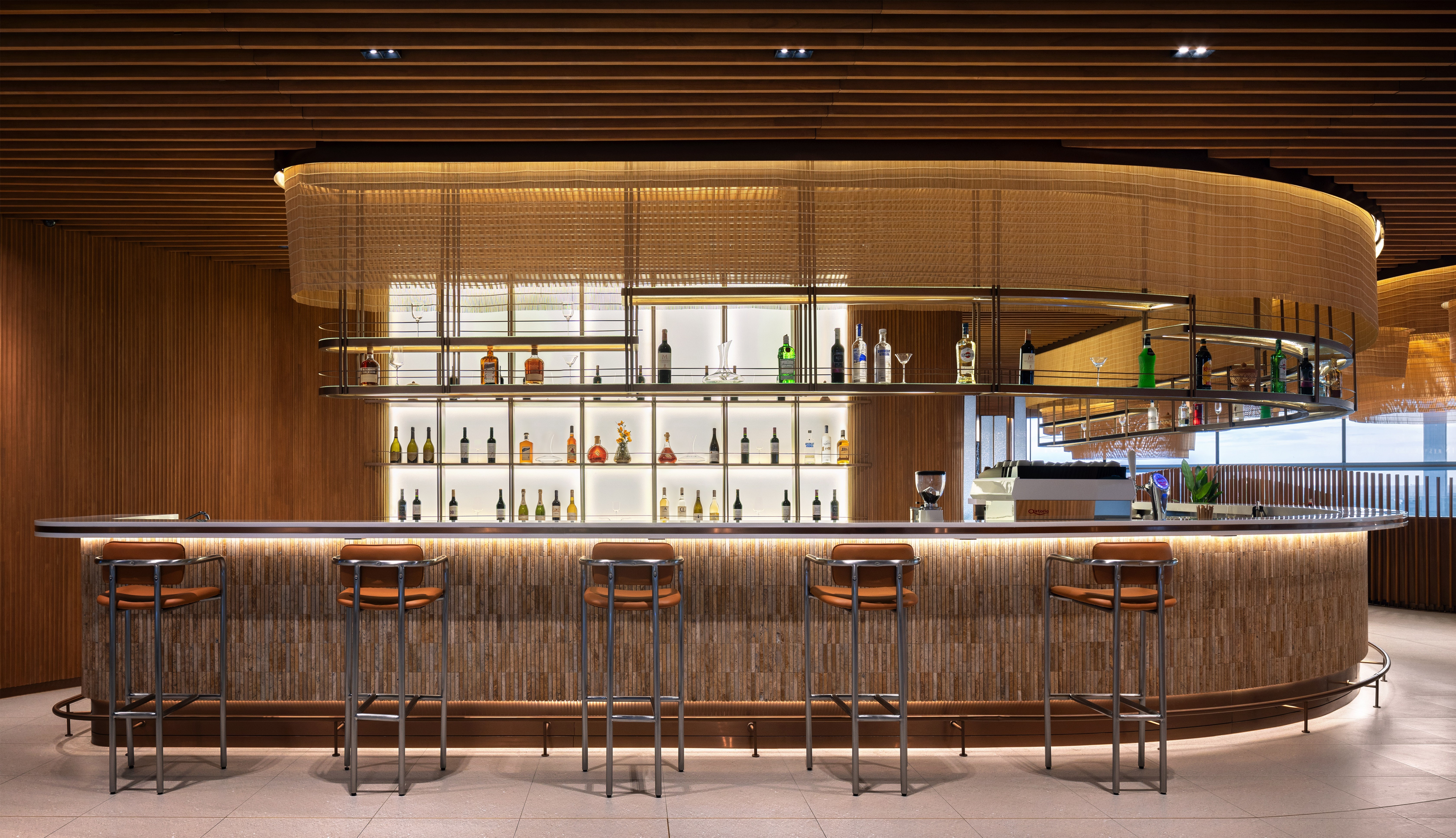 cambodian-hospitality-airport-bar-service Close-up of the textured stone bar at Malis Restaurant with warm lighting and a contemporary spirits display.