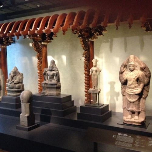 Ornate wooden arches and stone sculptures displayed in a museum exhibit.