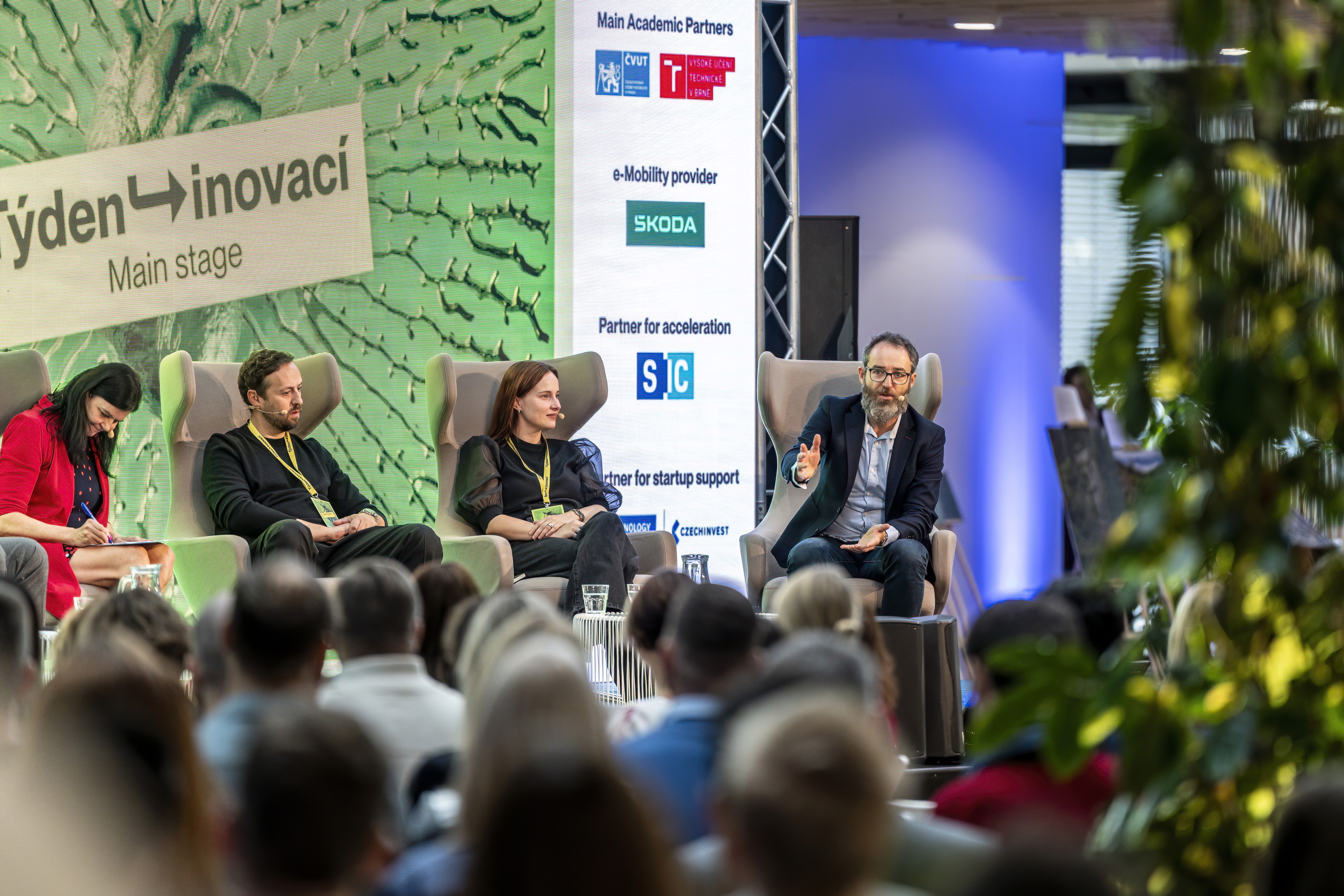 Panel discussion on the main stage of a business conference with an audience present.