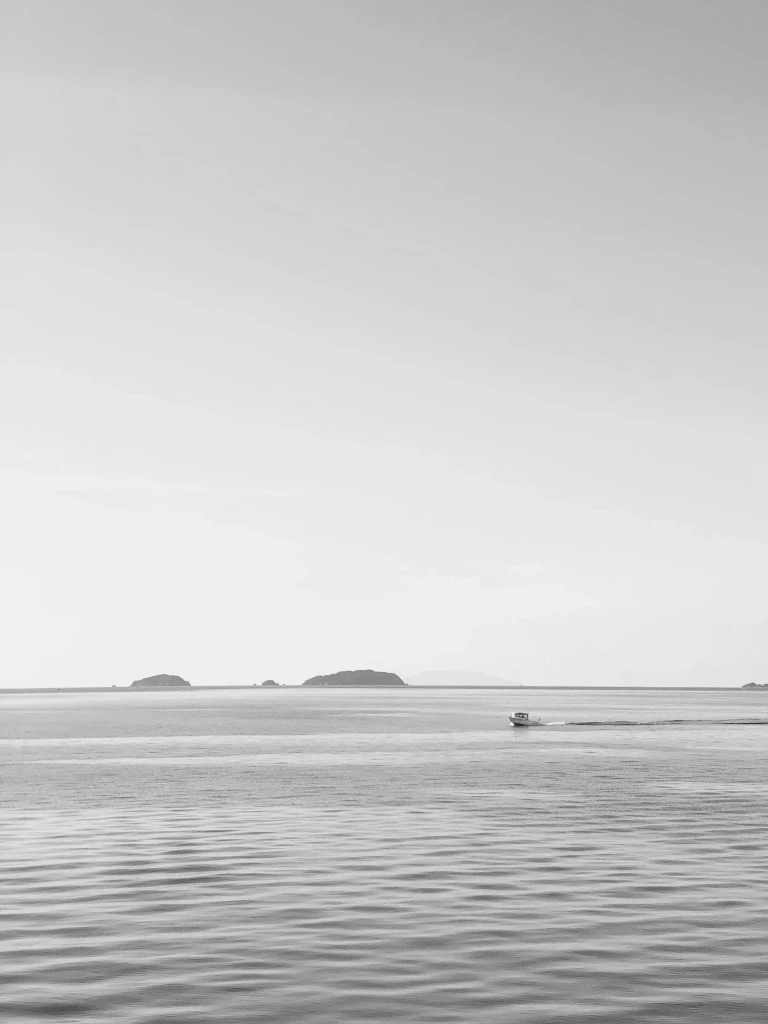 Boat on calm water under a grey sky in Auckland Harbour, New Zealand, a key private jet charter destination