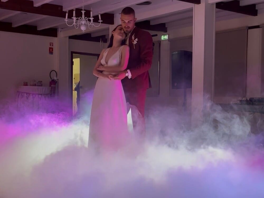Mariés sur la piste de danse avec effet nuage, fumée lourde et mise en lumière professionnelle pour une ouverture de bal.