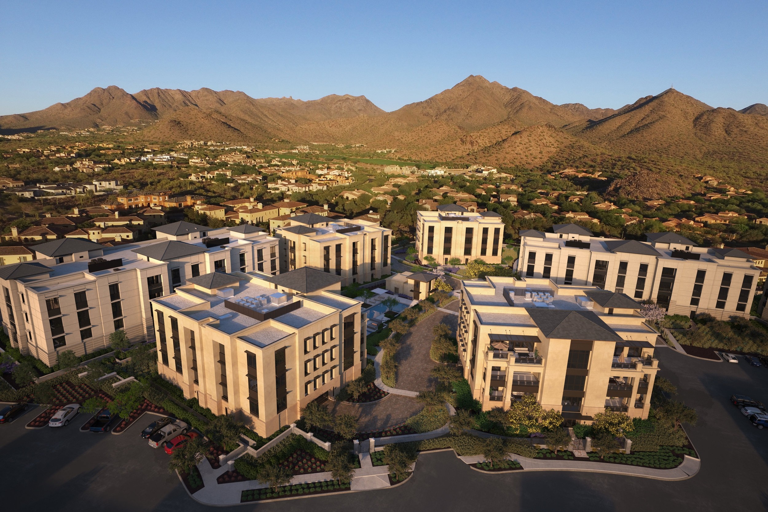 Aerial view of a luxury apartment complex nestled in a mountain valley. The buildings are modern and elegant, with a pool and landscaping visible.
