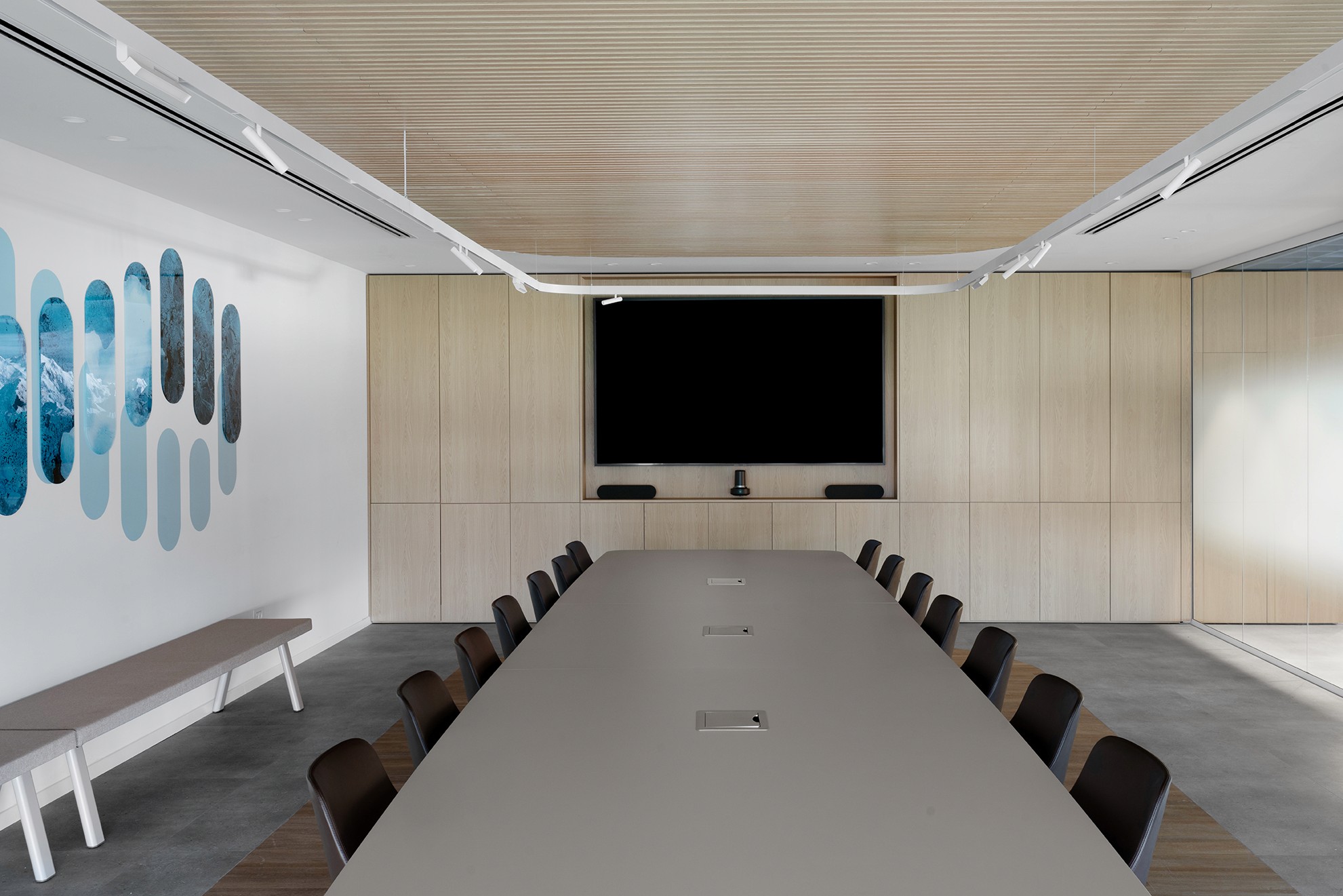 חדר דירקטוריון (Boardroom): עיצוב מינימליסטי ונקי עם שולחן ארוך, מסך מולטימדיה וחיפוי עץ בהיר לאווירה עסקית וממוקדת.