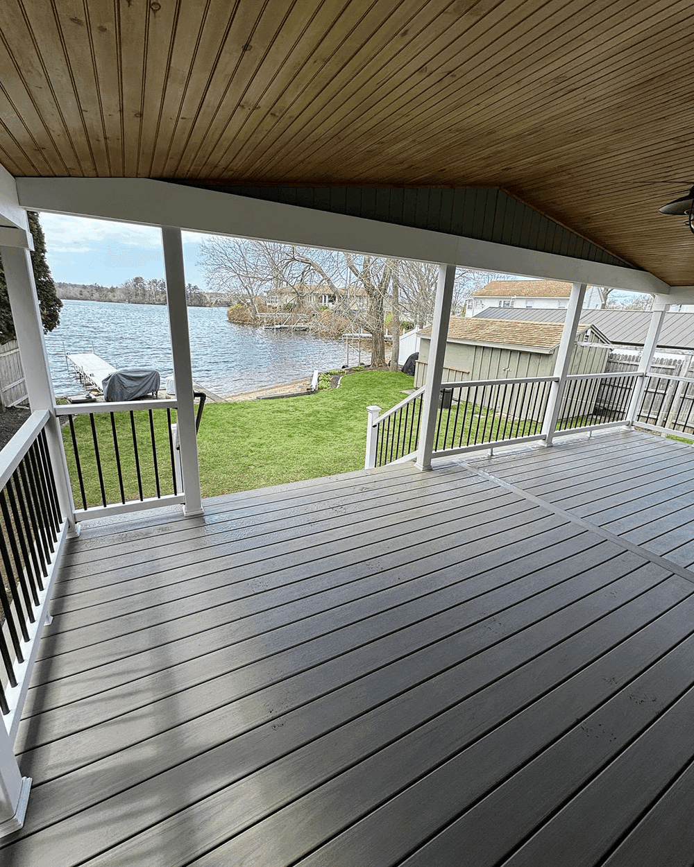 Grey Trex deck with white railings looking out at a lake with a dock