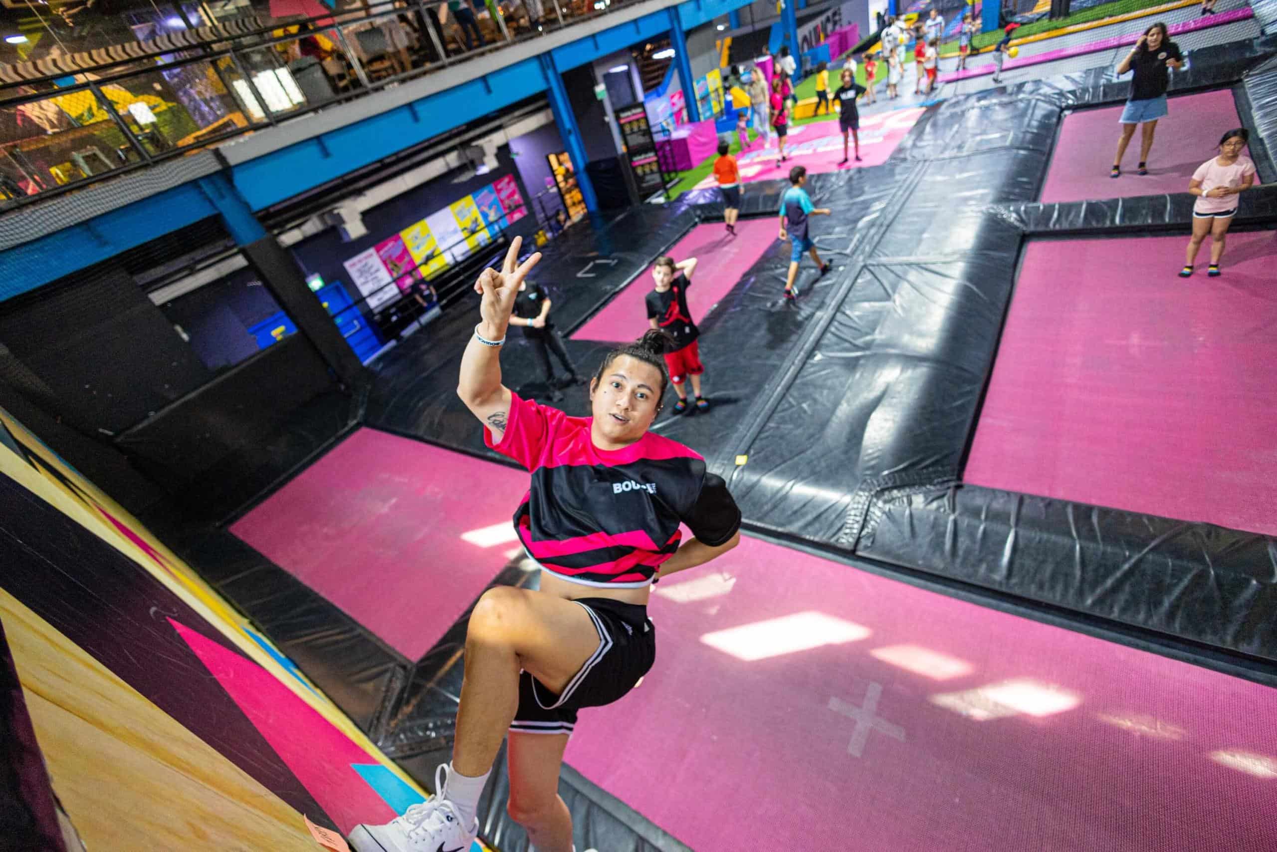 A man posing after jumping off a trampoline, with kids playing in the background, during things to do in Dubai with family.