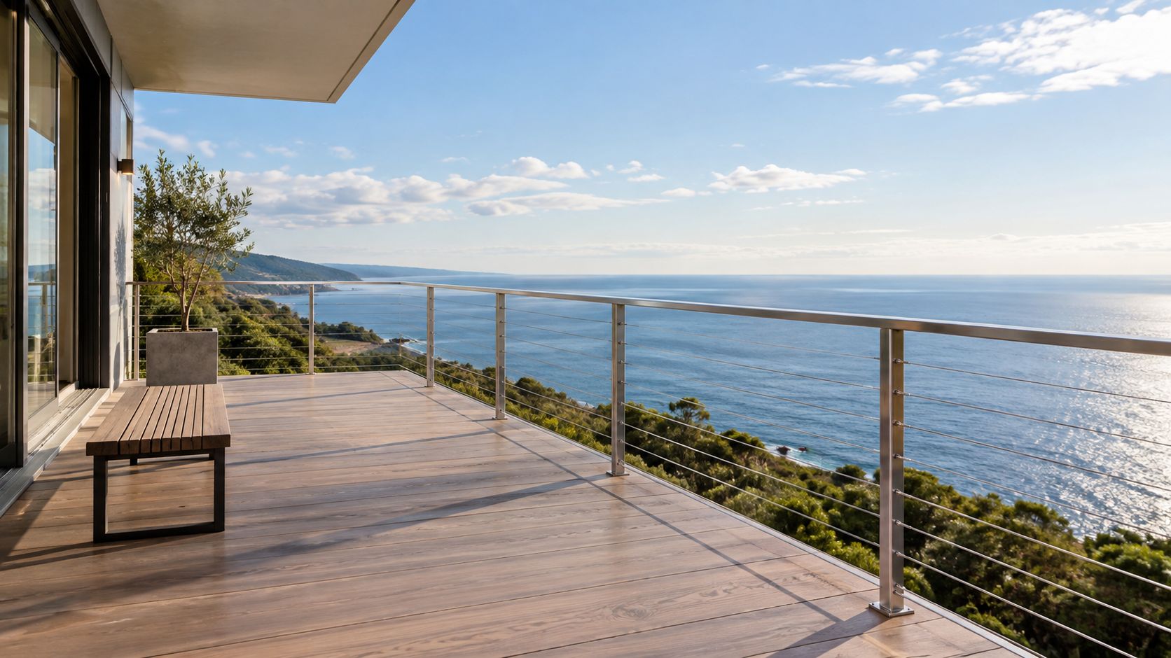 A scenic balcony with modern stainless steel cable railings overlooking the ocean on a sunny day.