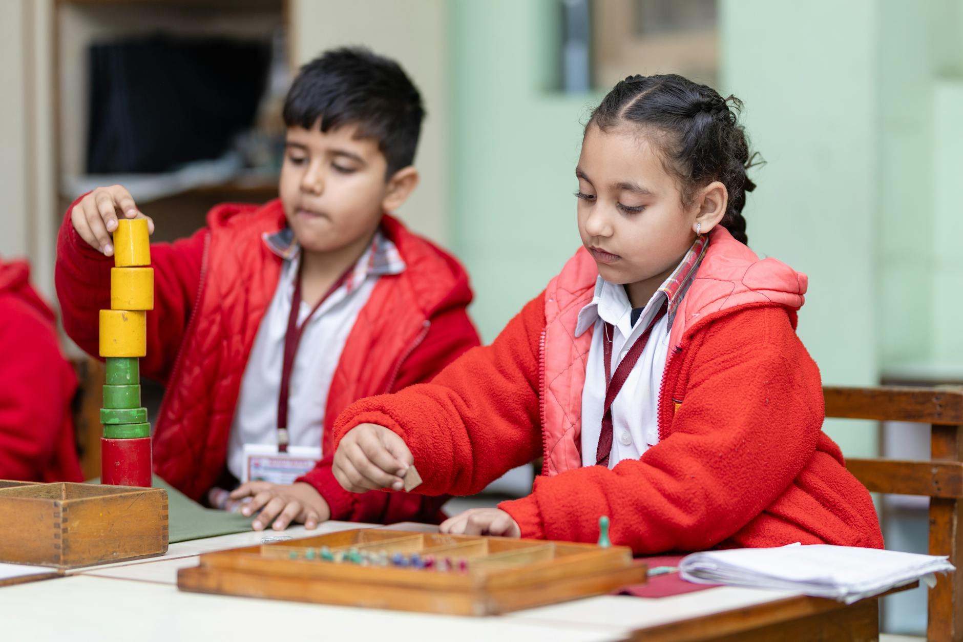 Elementary students building a complex bridge structure using wooden blocks and colorful craft materials.
