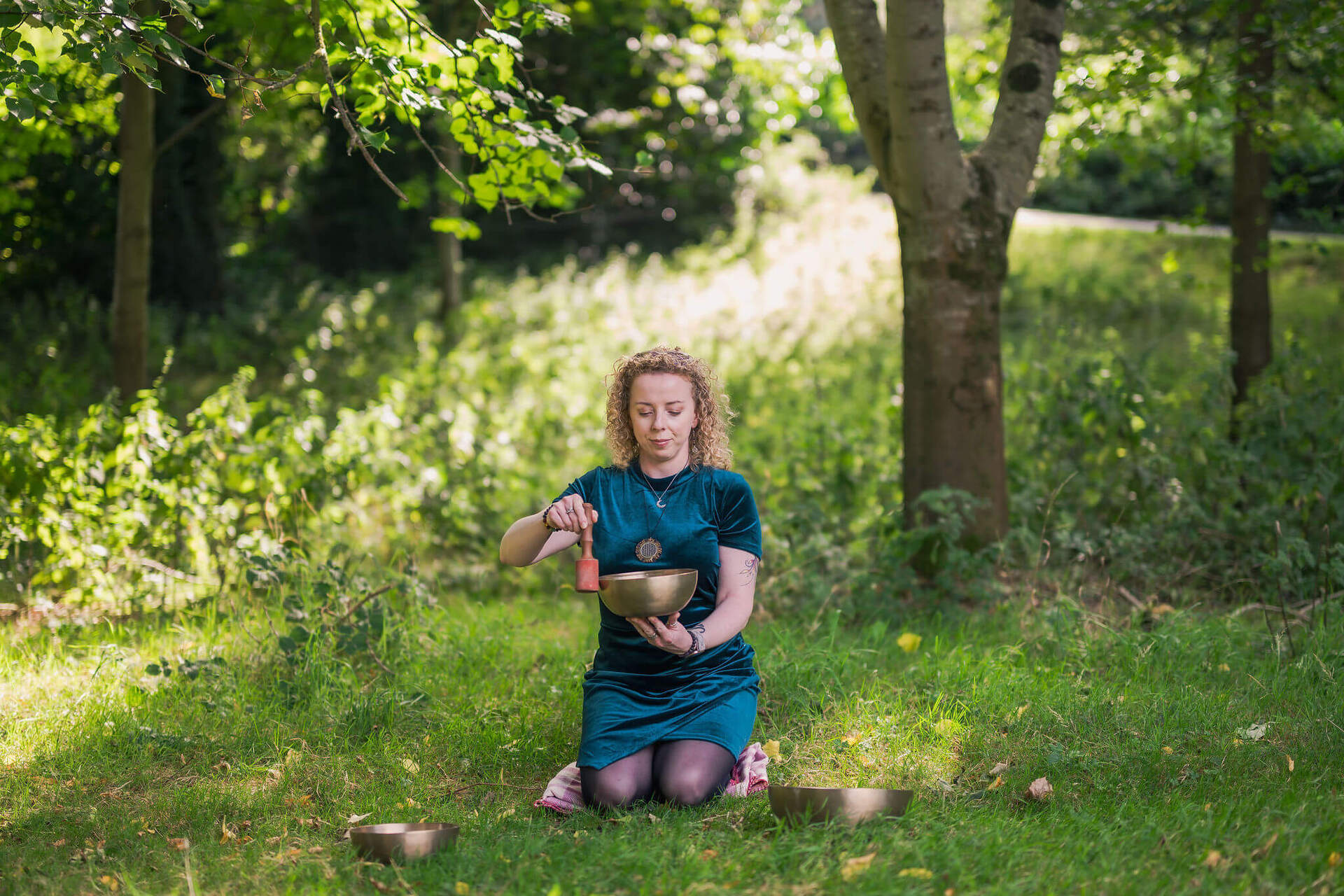 Maryrose using sound bowl while sitting in the woods