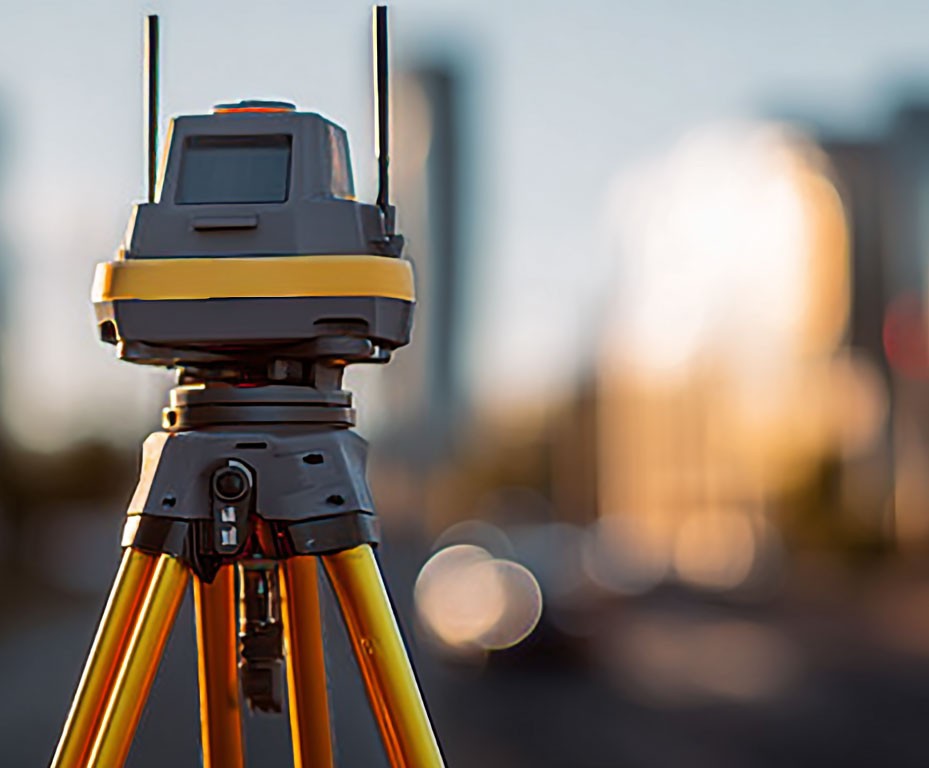 Professional land surveying equipment on tripod with blurred city background