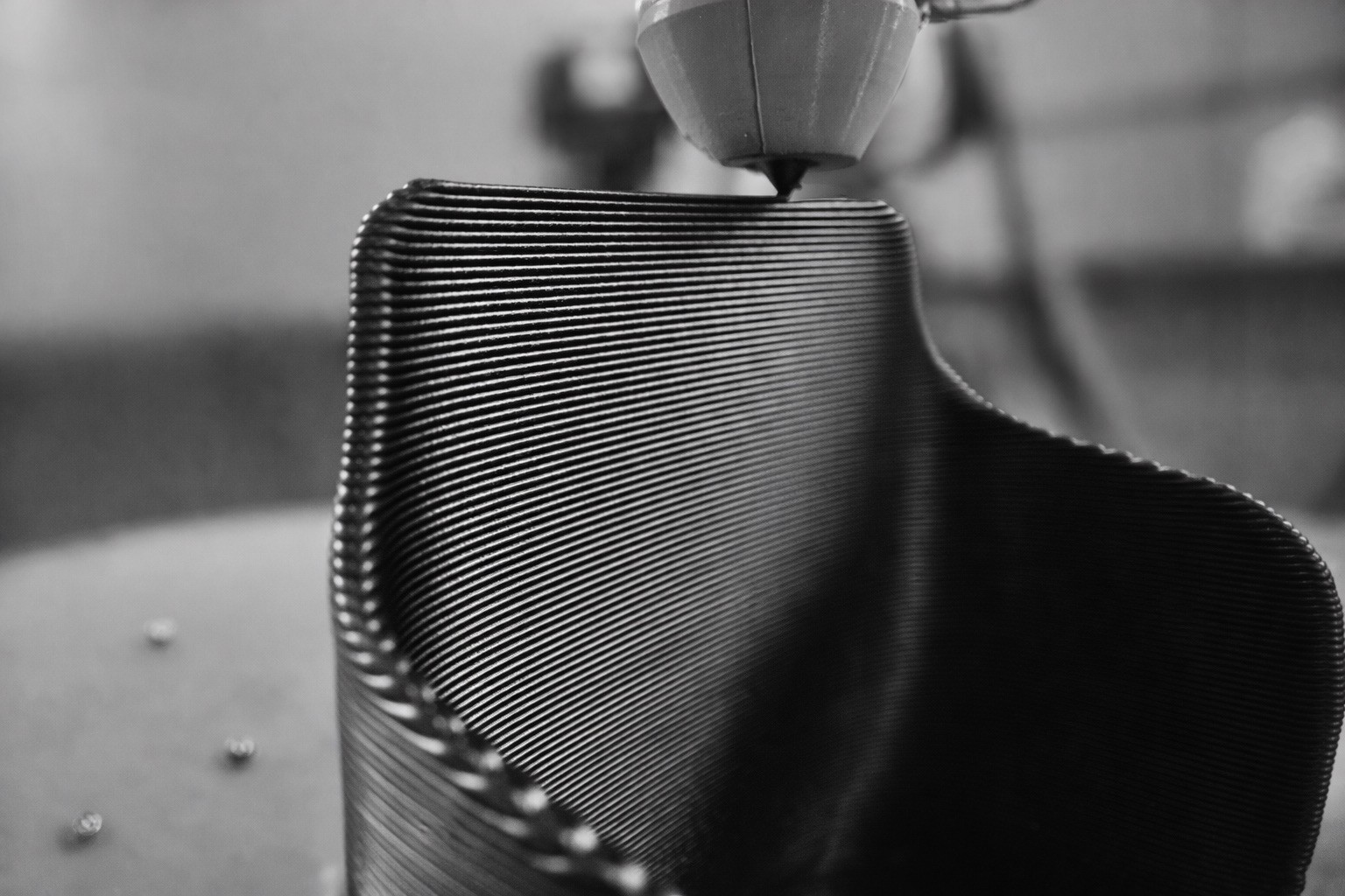 A high-contrast, black and white silhouette of a hand holding a square electronic component, likely a CPU or pin-grid array. The underside of the chip is facing the camera, showcasing a dense and perfectly aligned grid of tiny vertical pins.