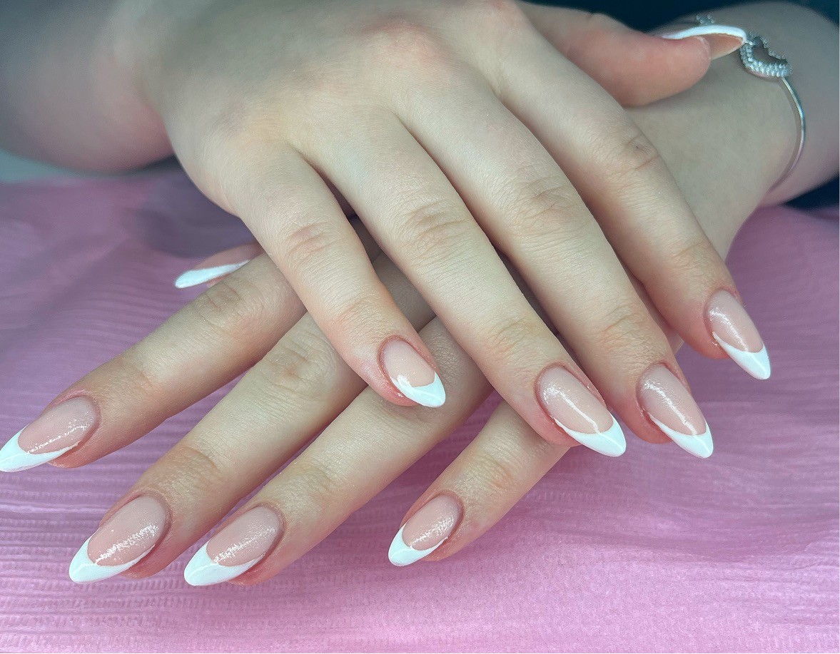 Hand with light pink nails and rings on cozy blanket