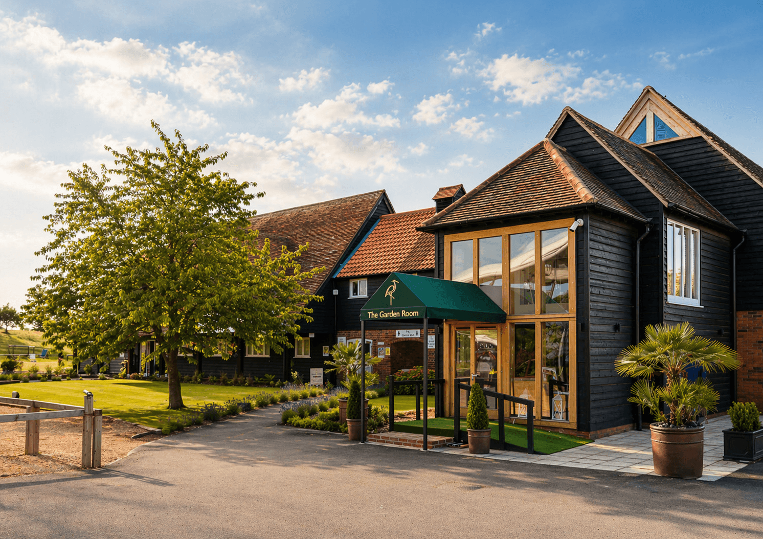 A charming rustic building with dark wood siding and a red-tiled roof houses "The Garden Room," 