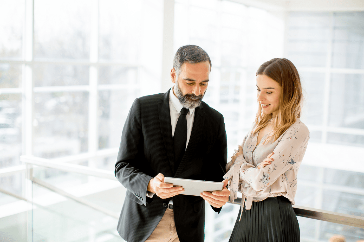 Senior Businessman and Young Businesswoman with Tablet in Office