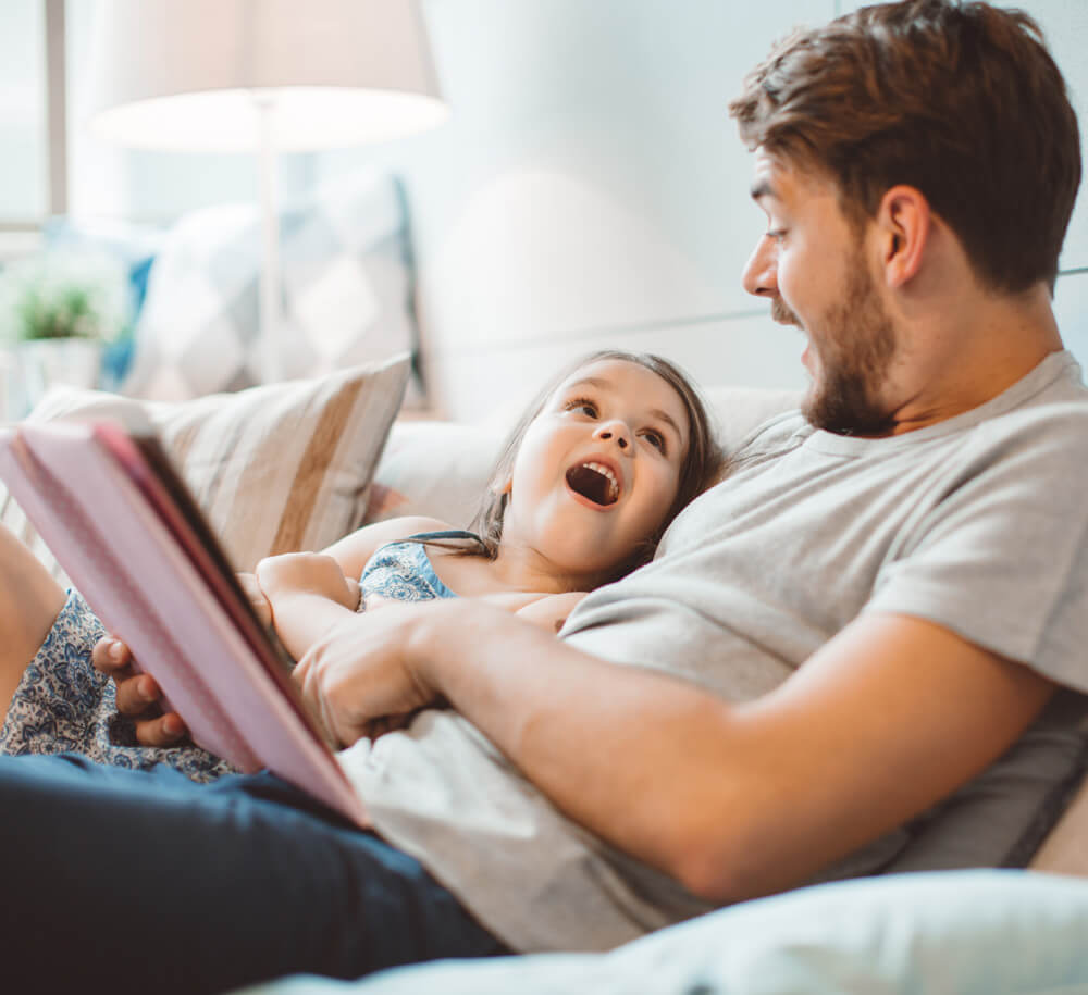 dad with daughter reading a book together