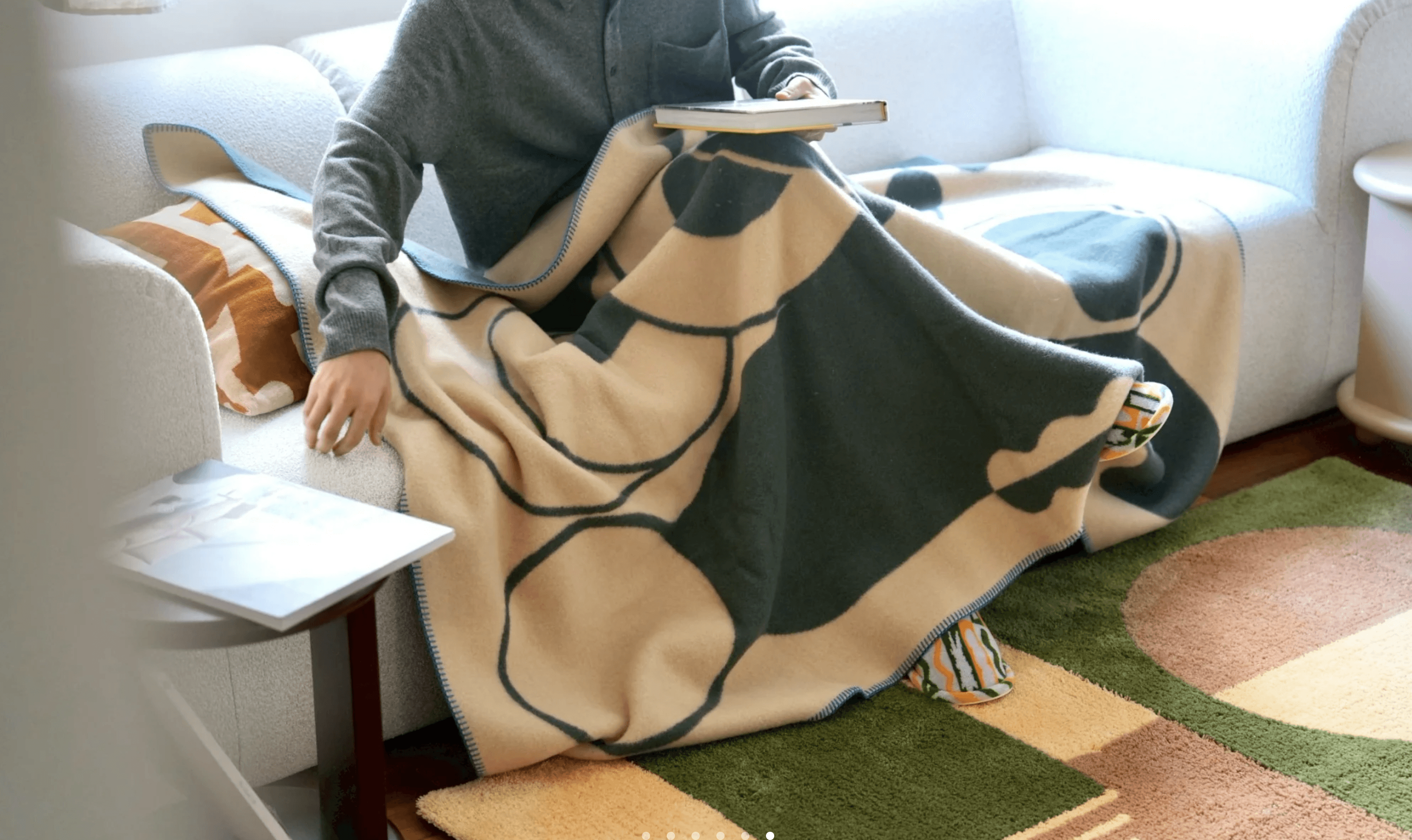 MY TONE woven blanket featuring Josephine Grenier’s graphic pattern draped over someone on a sofa.