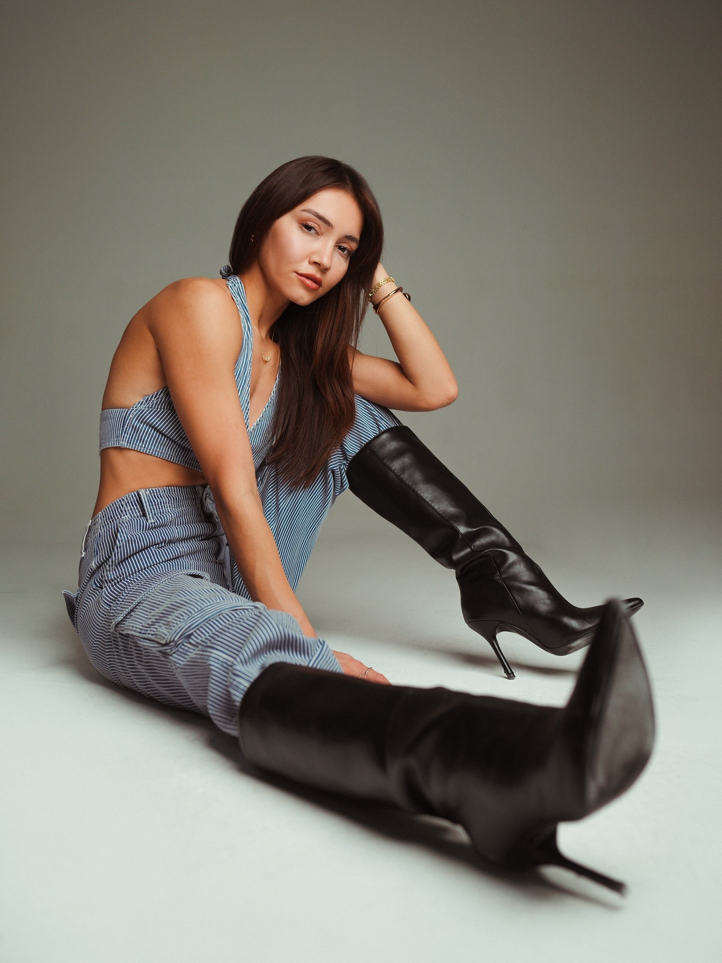 Close-up portrait of a freckled woman with soft pink hair and star earring, natural light, white tank top.